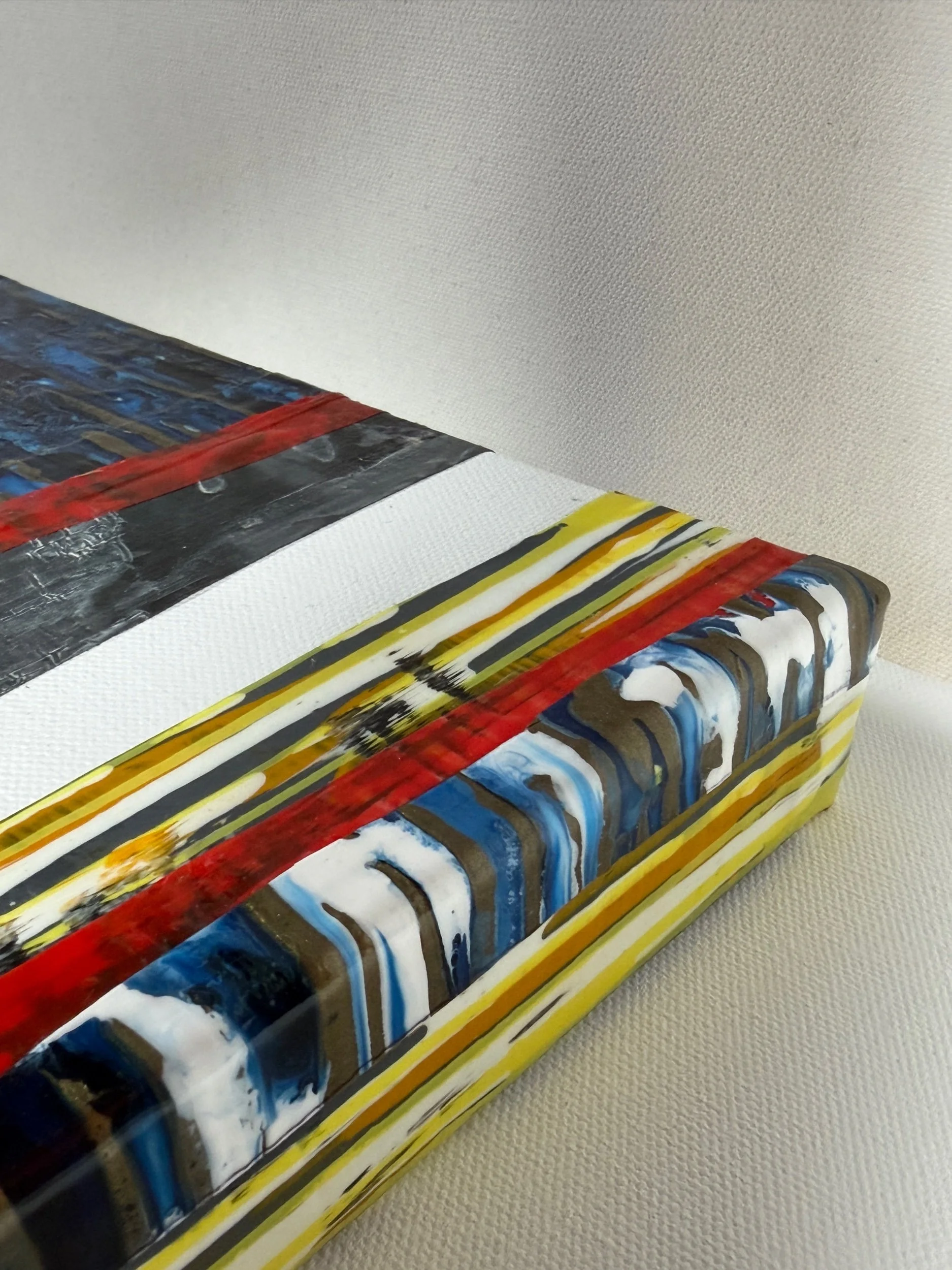 Detail of Countercurrent’s red and yellow bands and glossy layered corner.