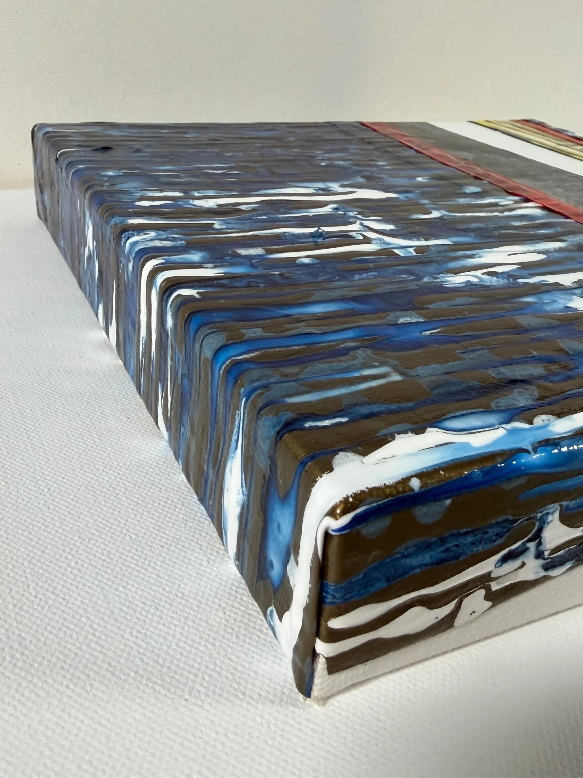 Close-up of blue, white, and gold painted gloss sheets along Countercurrent’s wrapped edge.