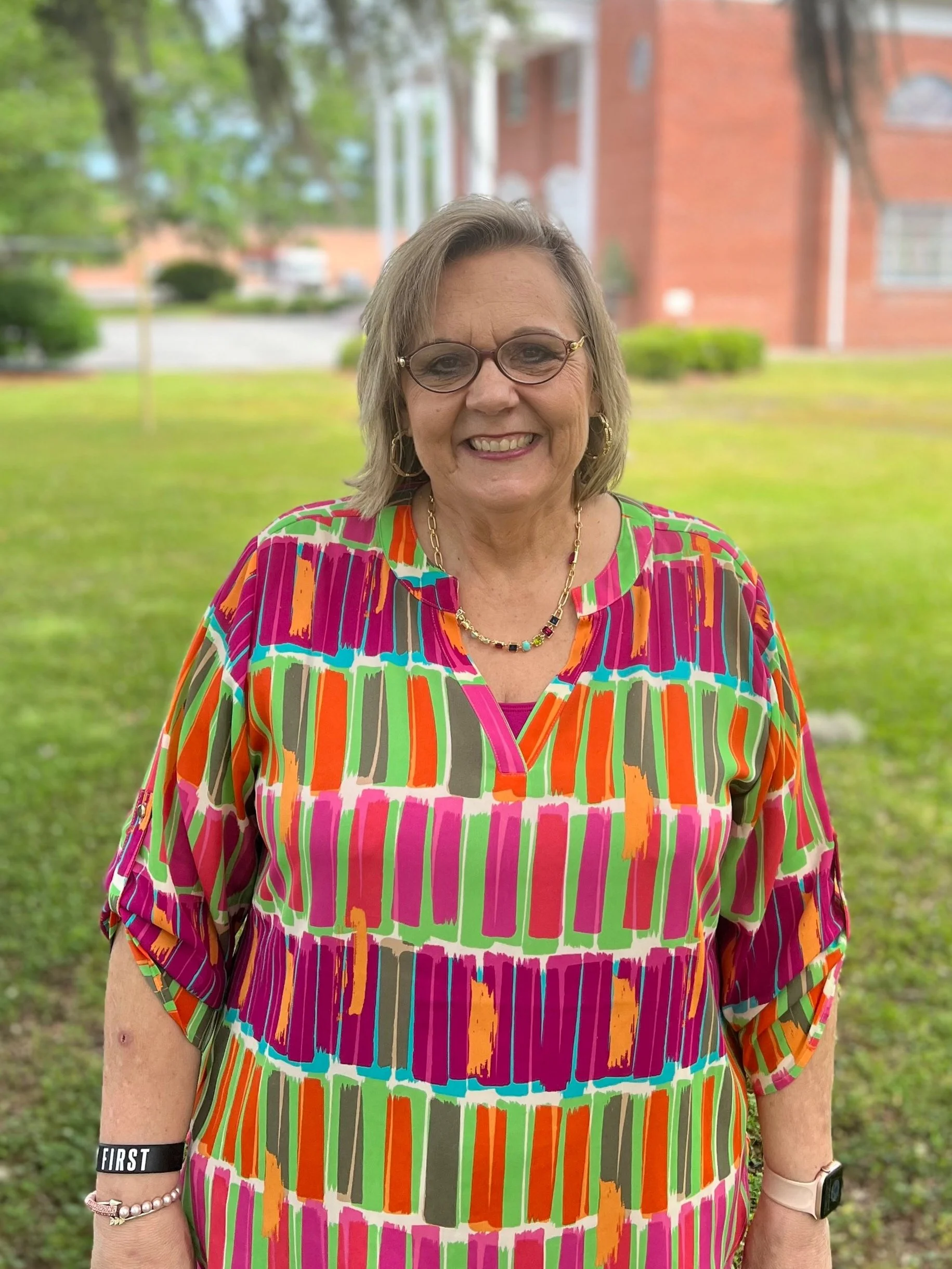 Person smiling outdoors in colorful shirt with nature background