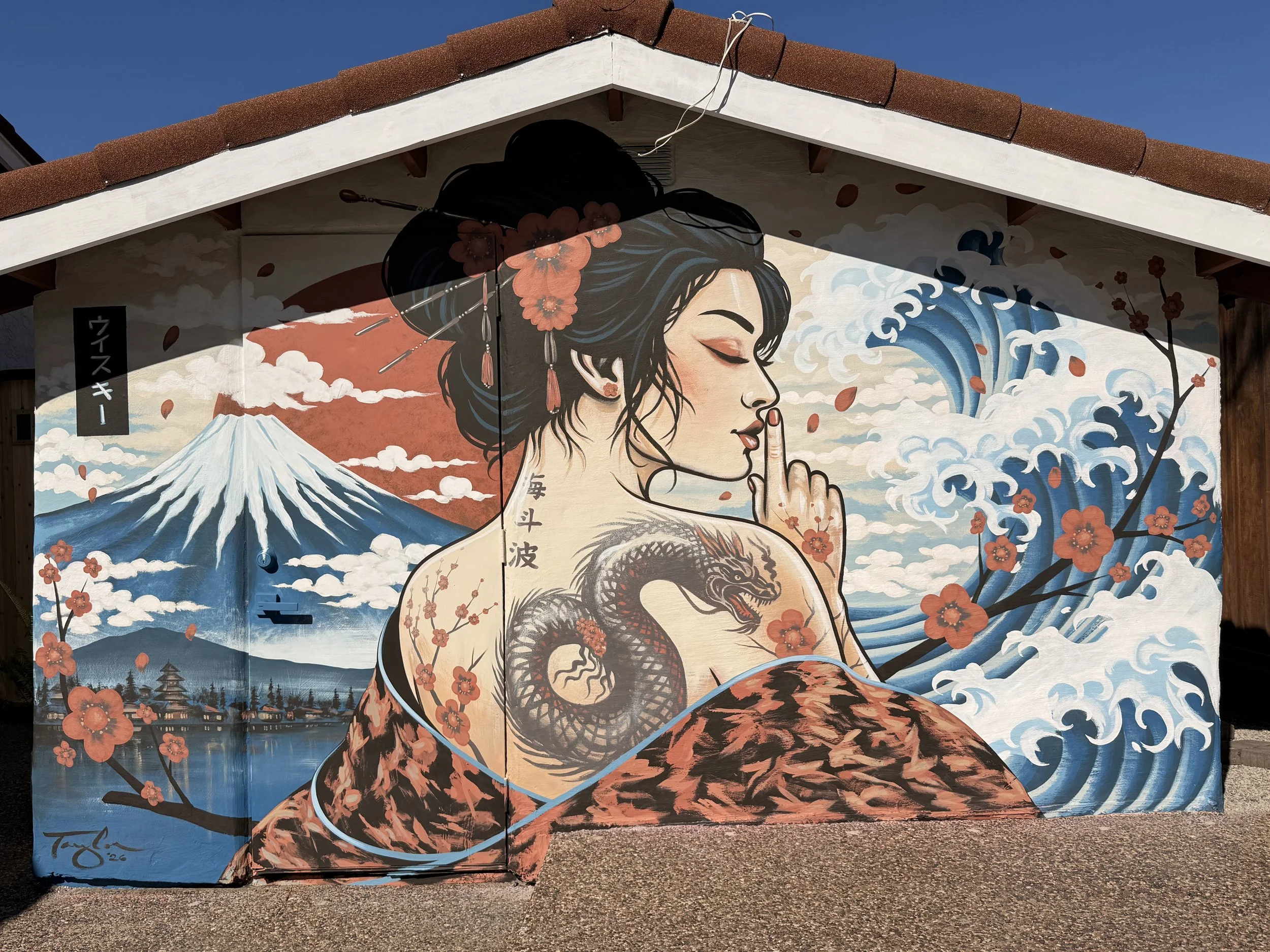 An image of a mural with a Japanese Geisha, with a painted tattoo of a dragon, with Mount Fuji, with a recreation of the Great Wave by Hokusai.