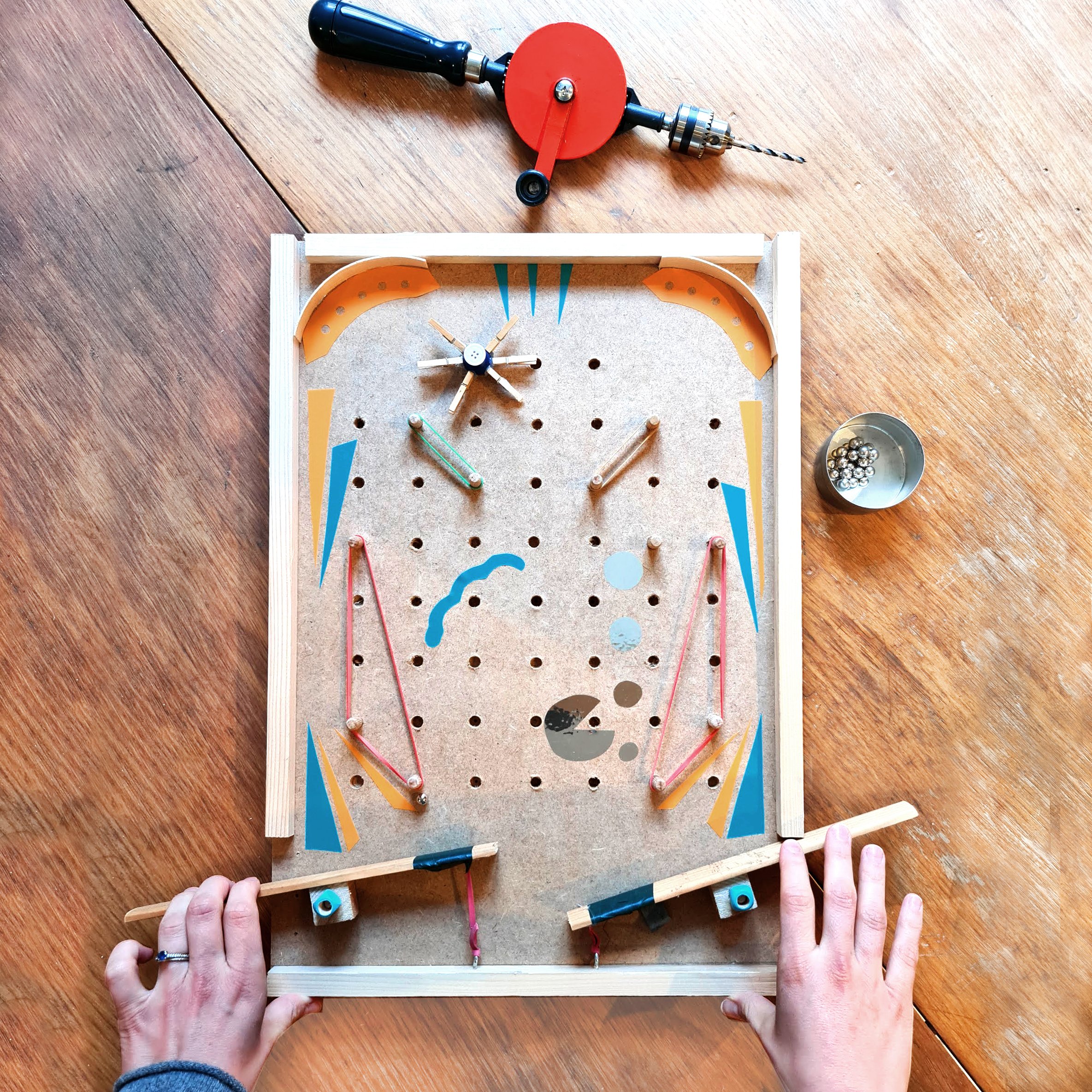 Vue du dessus d'un jeu de fipper en bois avec des éléments avec une perceuse manuelle ou chignole