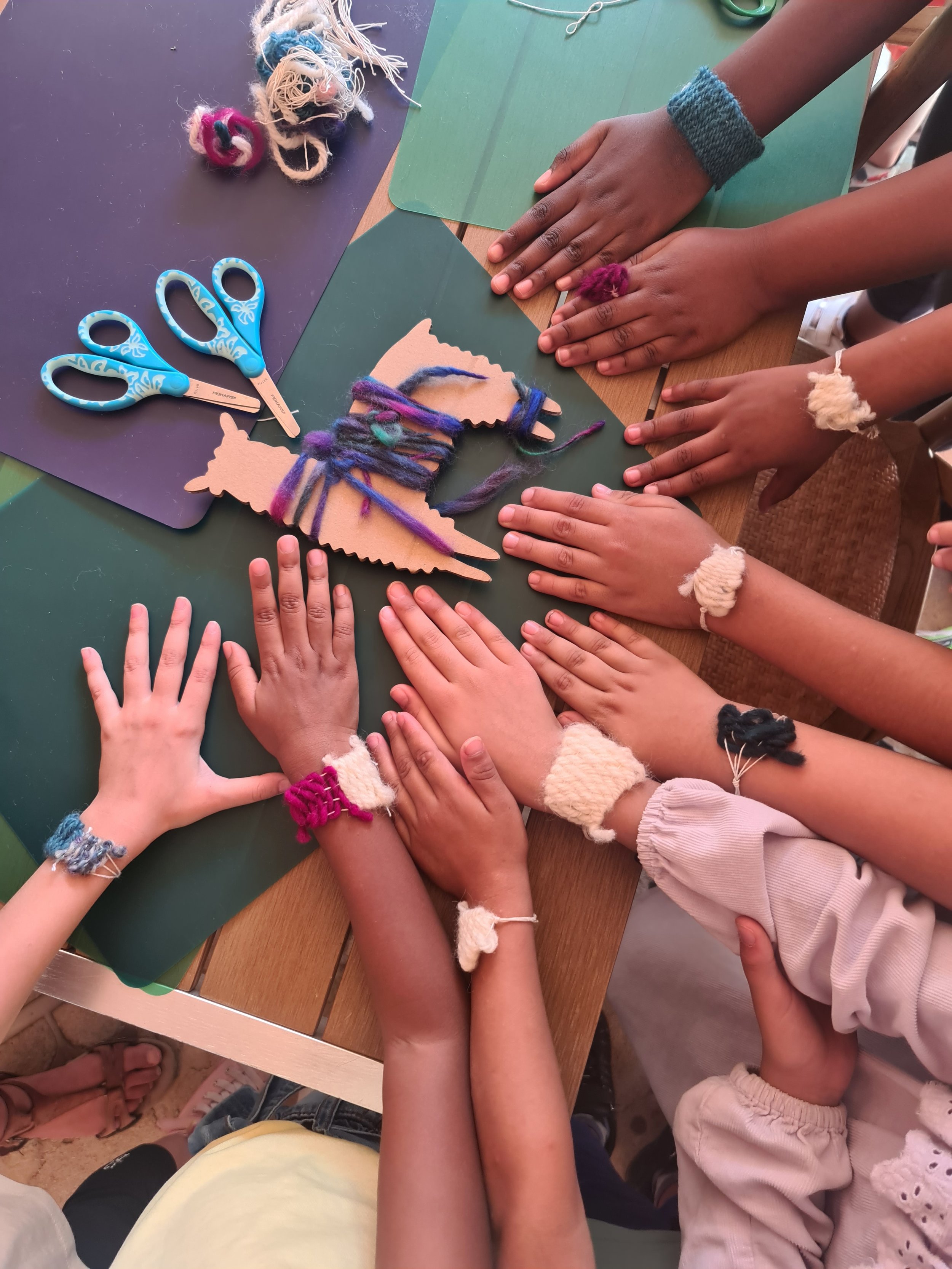 Mains d'enfants exposant leurs bracelet fabriqués par eux-même pendant un atelier créatif au Monde Nouveau de Montpellier