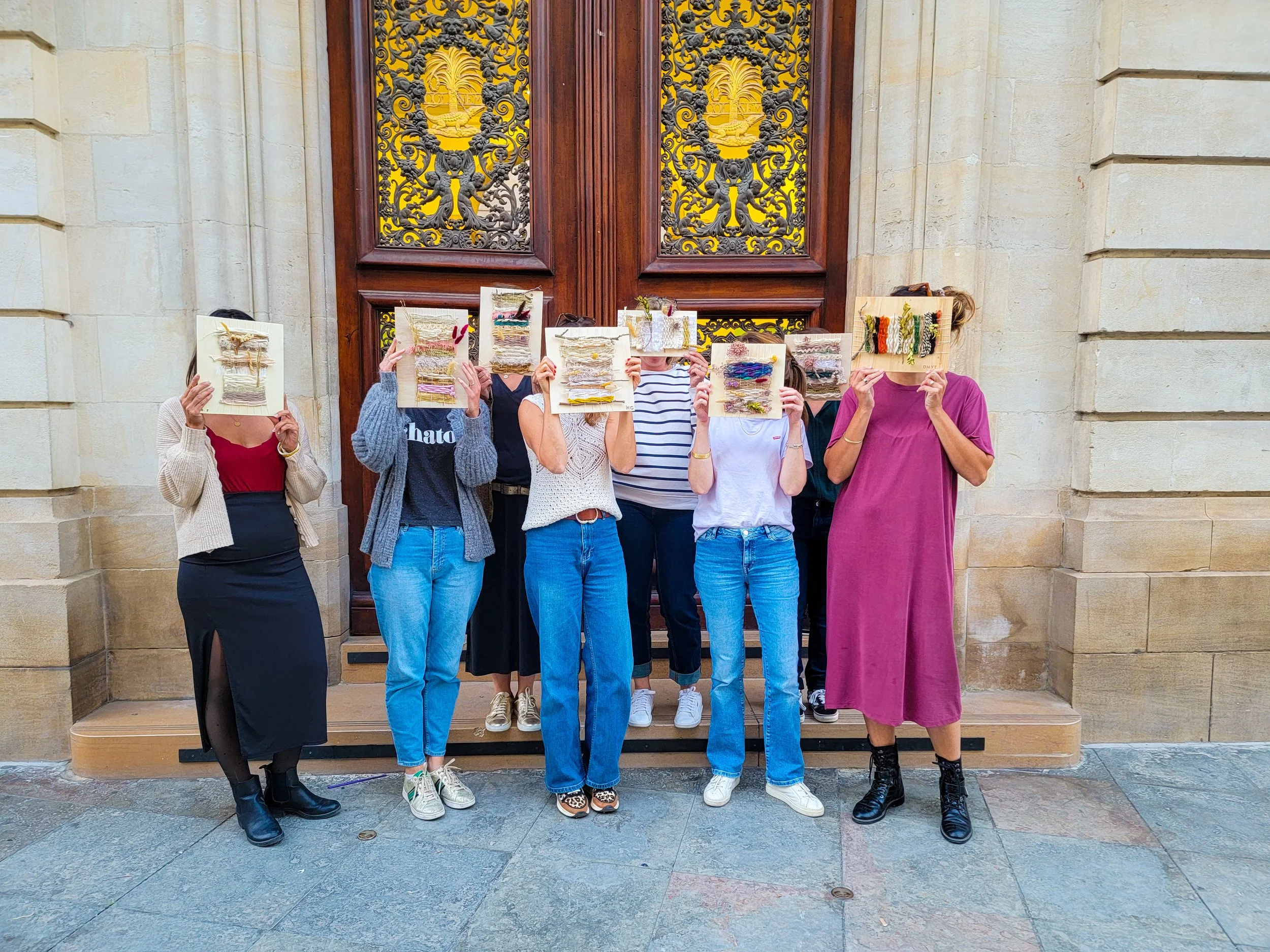Groupe de huit personnes pour un EVJF enterrement de vie de jeune fille, tenant des œuvres en bois et textile.