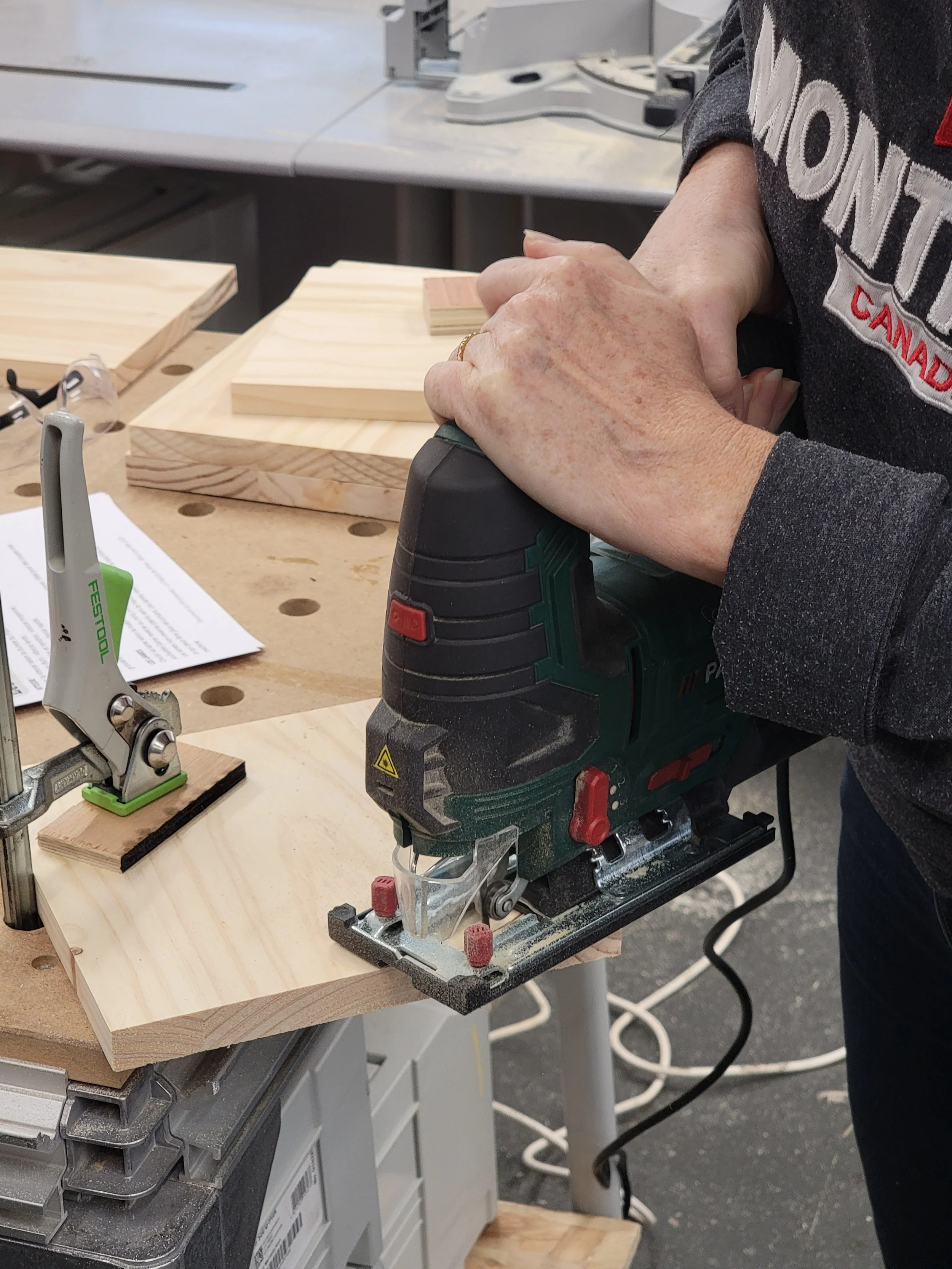 Une personne utilisant une scie électrique pour couper un morceau de bois dans un atelier de menuiserie.