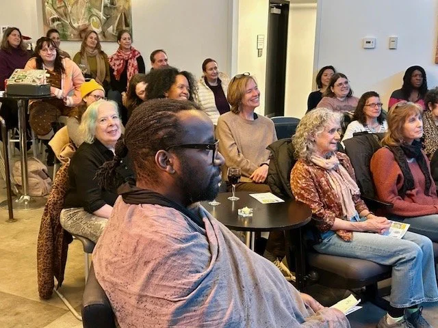 Audience members smiling and laughing during a live storytelling and stand-up comedy event featuring Michelle Courtney Berry, poet, performer, speaker, and humorist.
