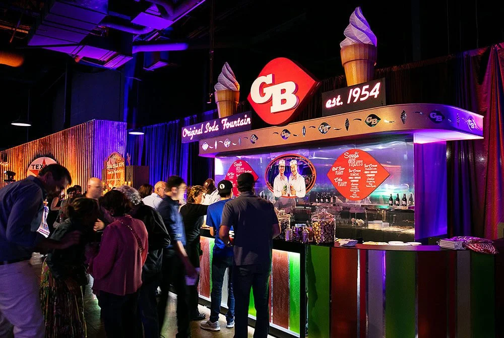 People enjoying themselves at a themed event with a colorful and festive bar setup.