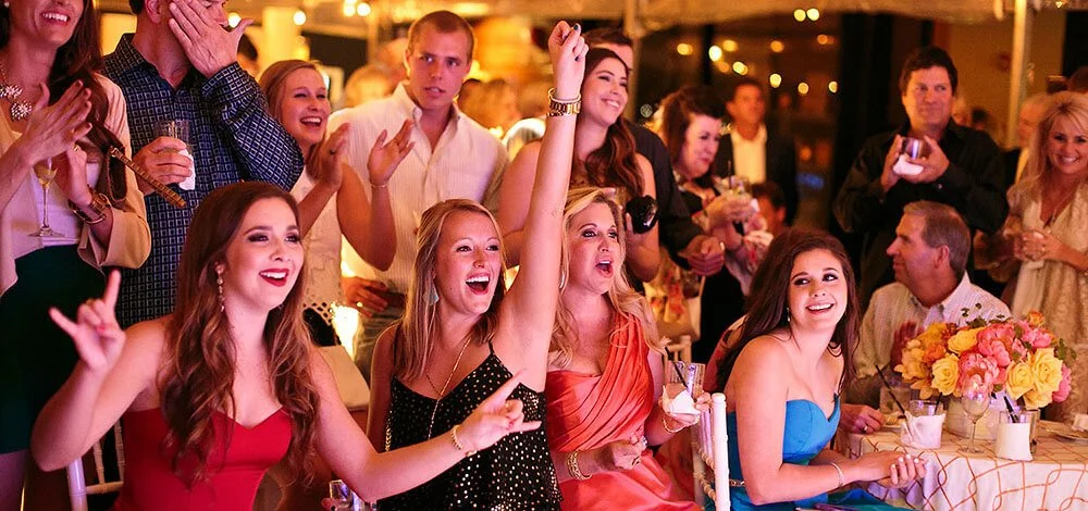 Group of people dancing and celebrating at a party, with joyful expressions and festive attire.