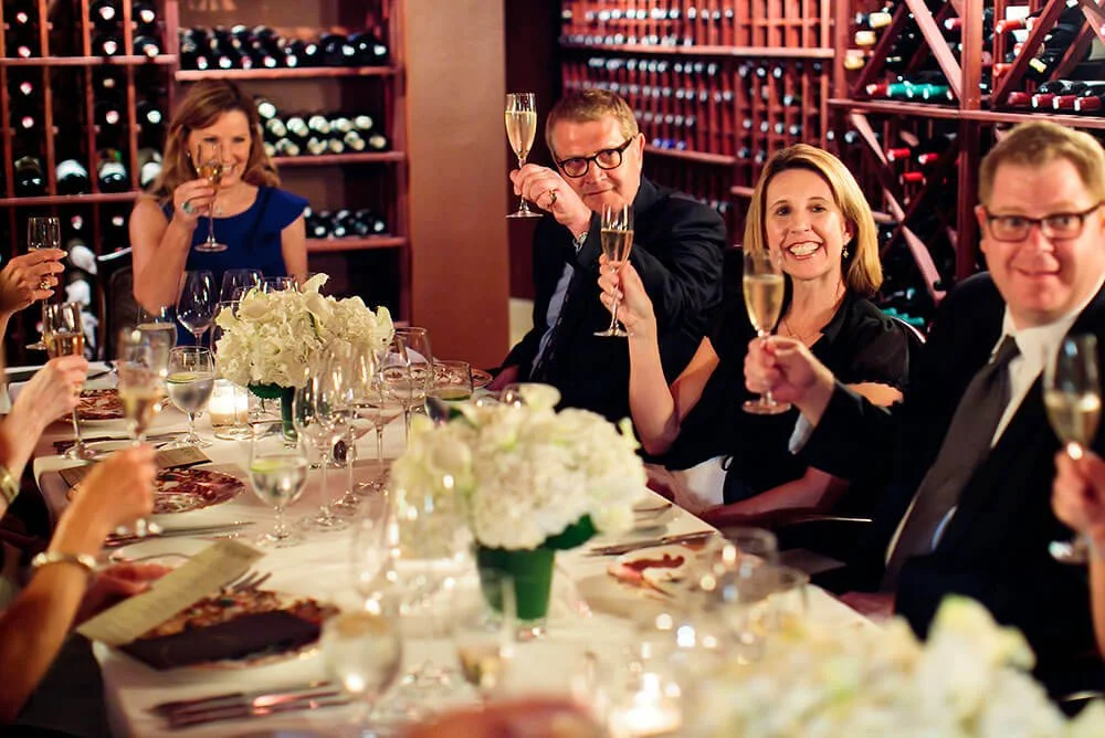 Group of people enjoying a fine dining experience, seated at an elegantly set table.