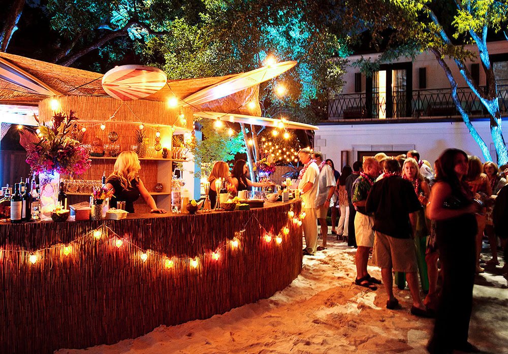 Outdoor bar area decorated with string lights, with guests socializing and enjoying drinks.