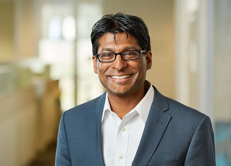 Headshot of man smiling with office space in background