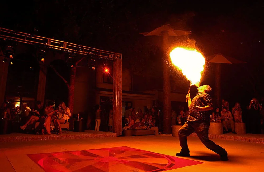 Fire performer breathing flames during an outdoor show, captivating the audience.