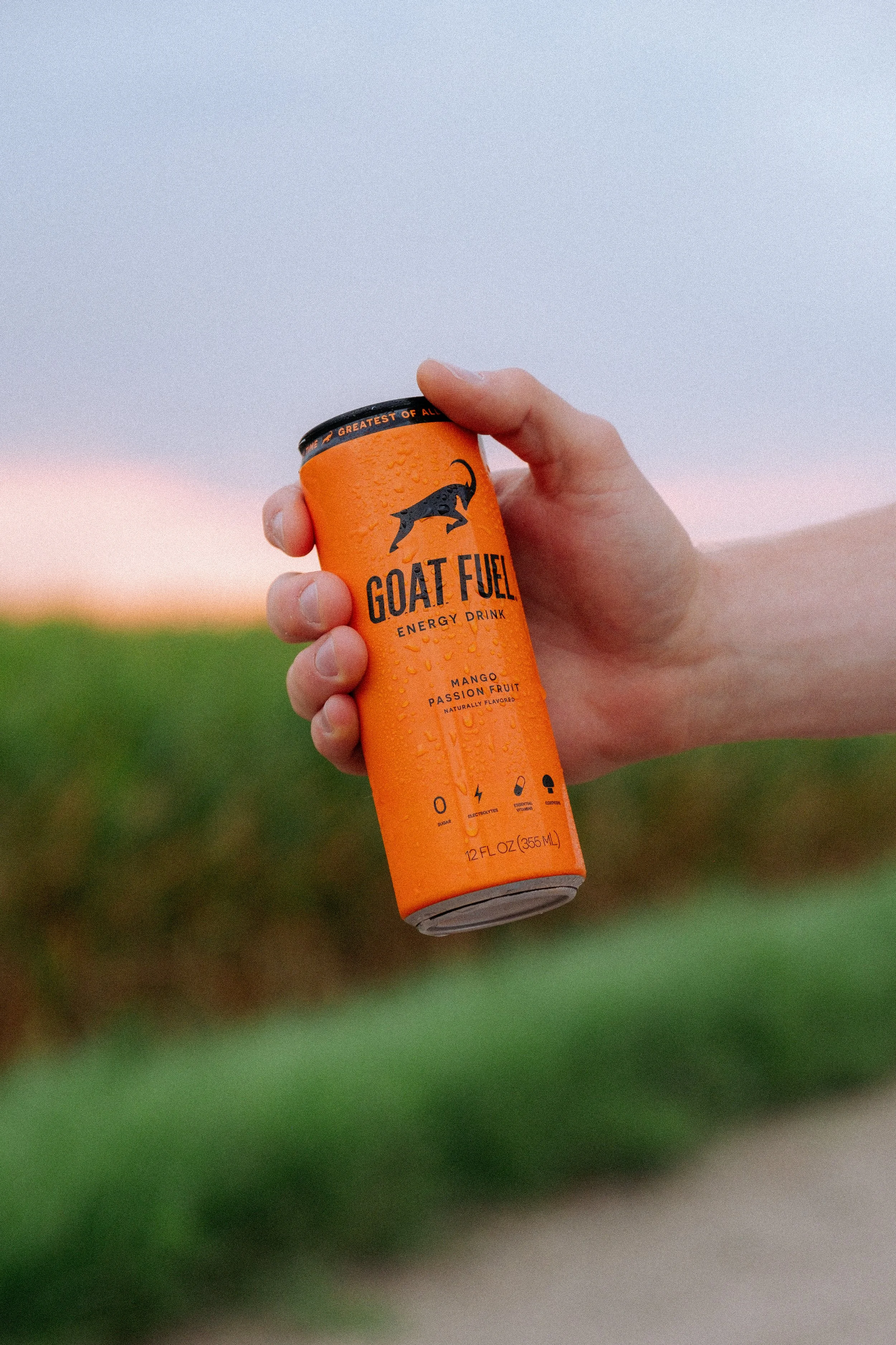 Male hand holding Mango flavored Goat Fuel.