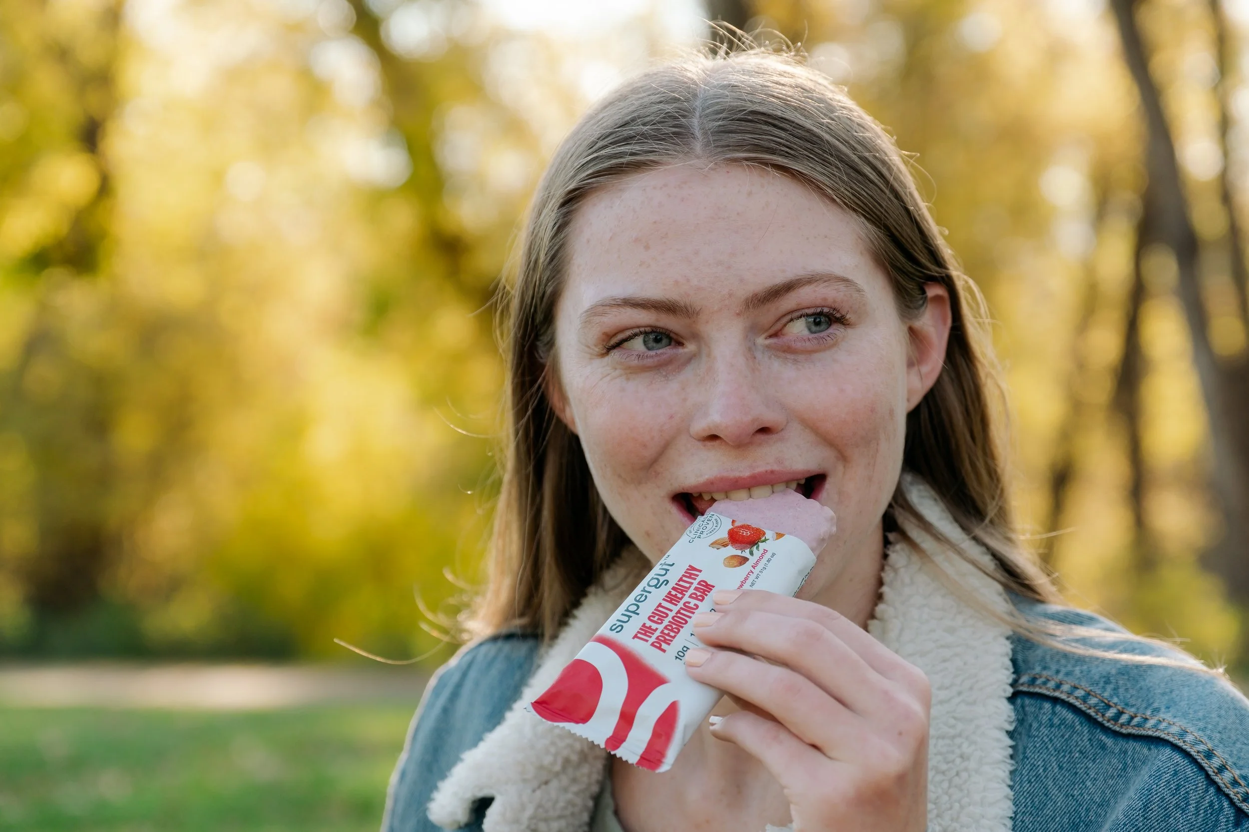 White girl taking bite of Supergut bar.