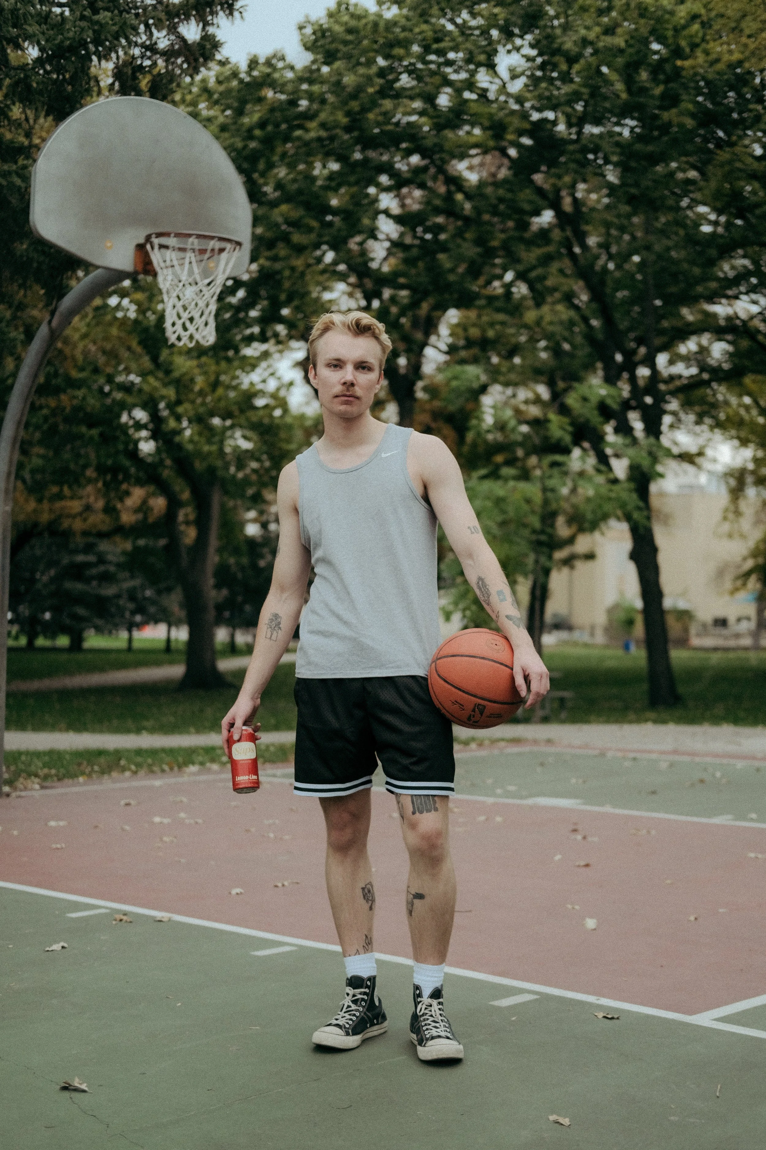 Man on basketball court with basketball in one hand and Sap's in the other.