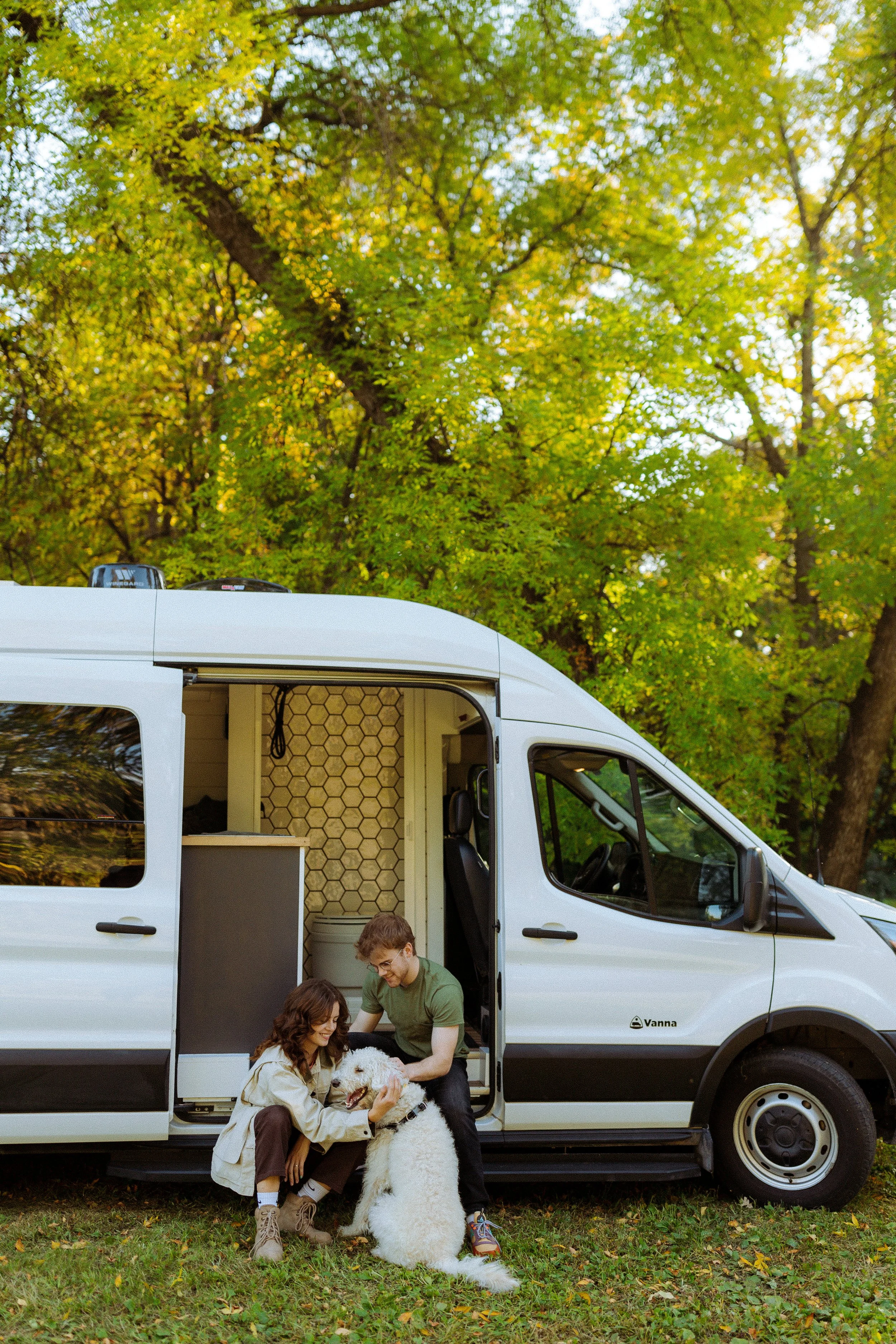 Man and woman petting their dog in front of Vanna Adventure Van.
