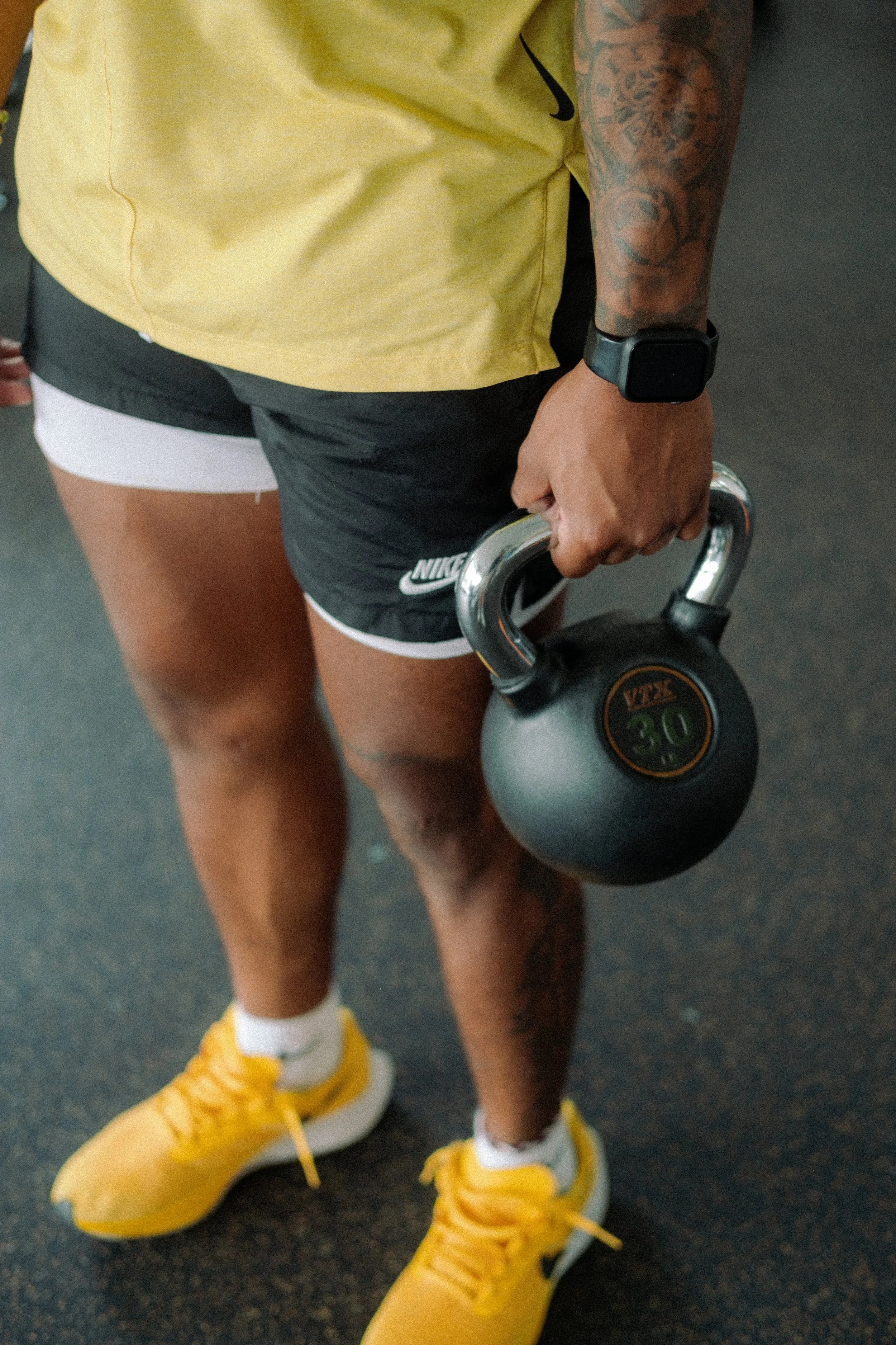 Black man holding kettle bell with apple watch on wrist.