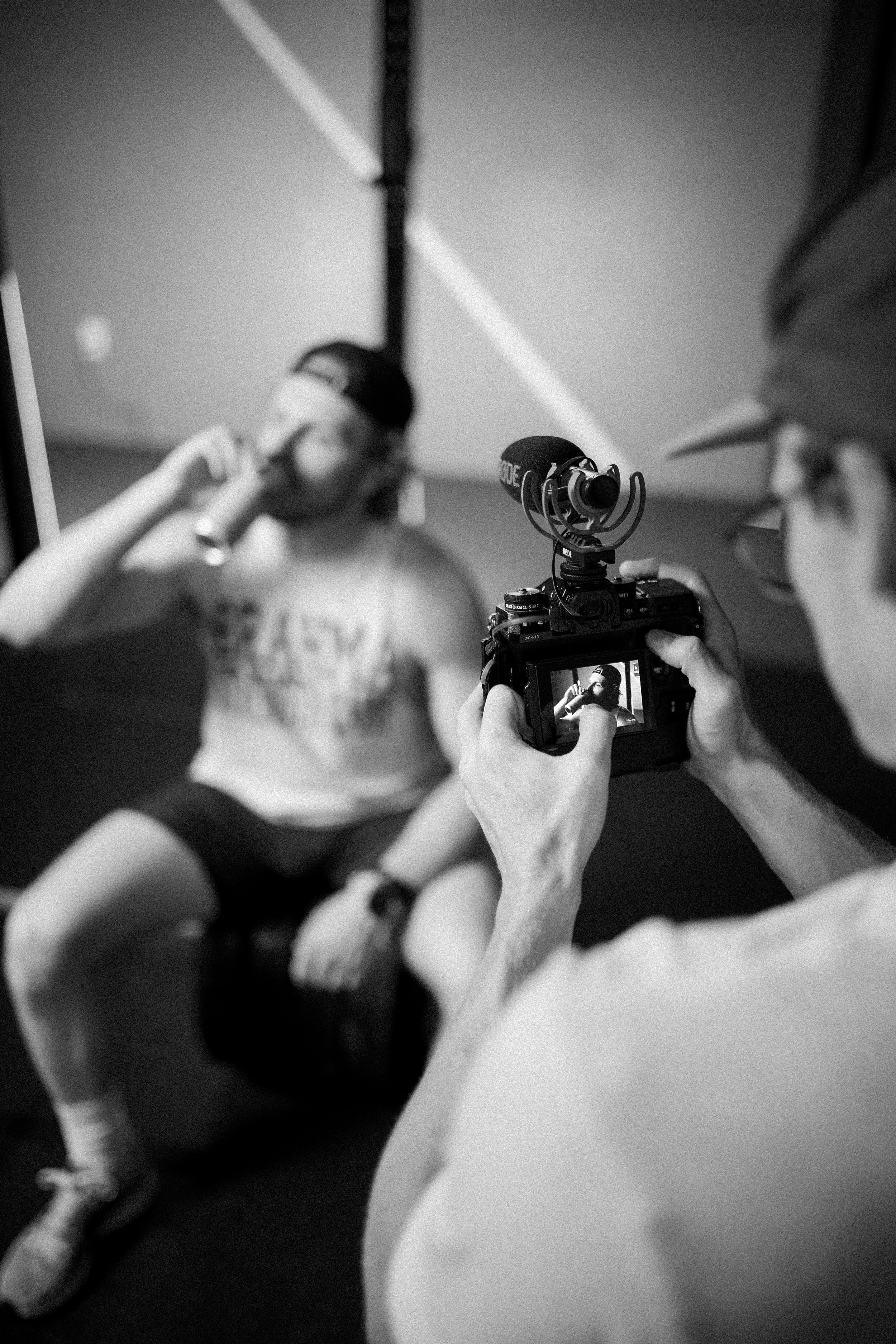 Man filming other man drinking energy drink at the gym.