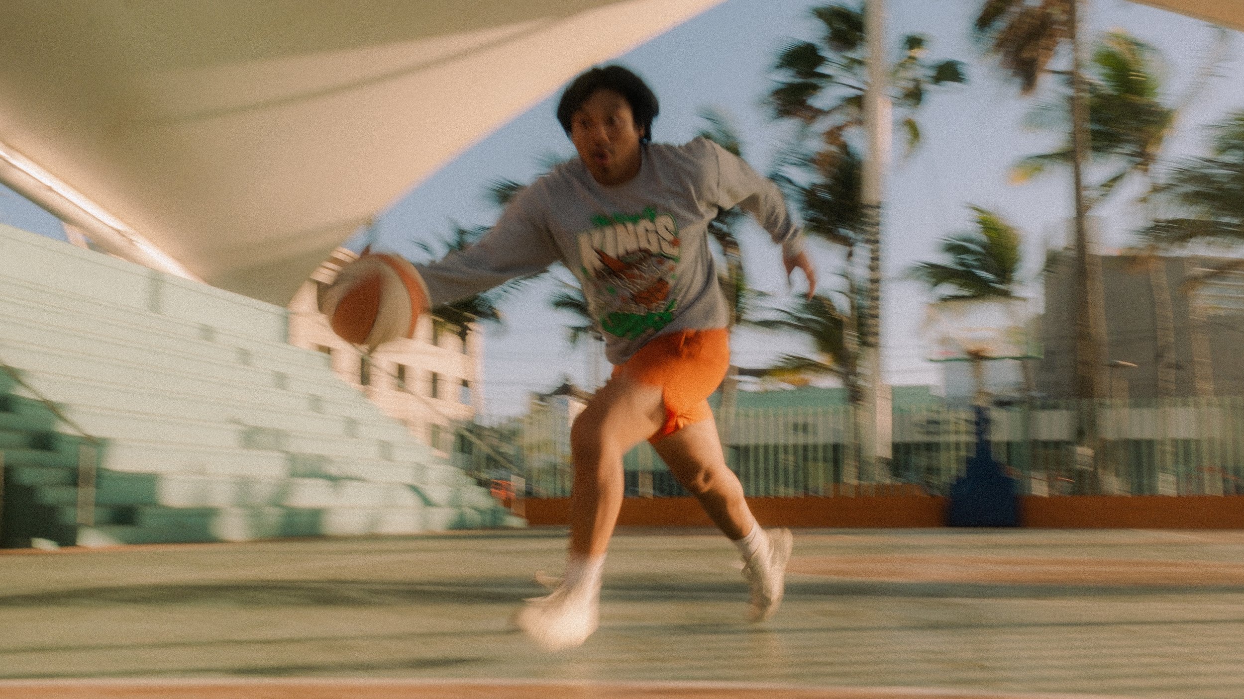 Man playing dribbling basketball on an outdoor basketball court.