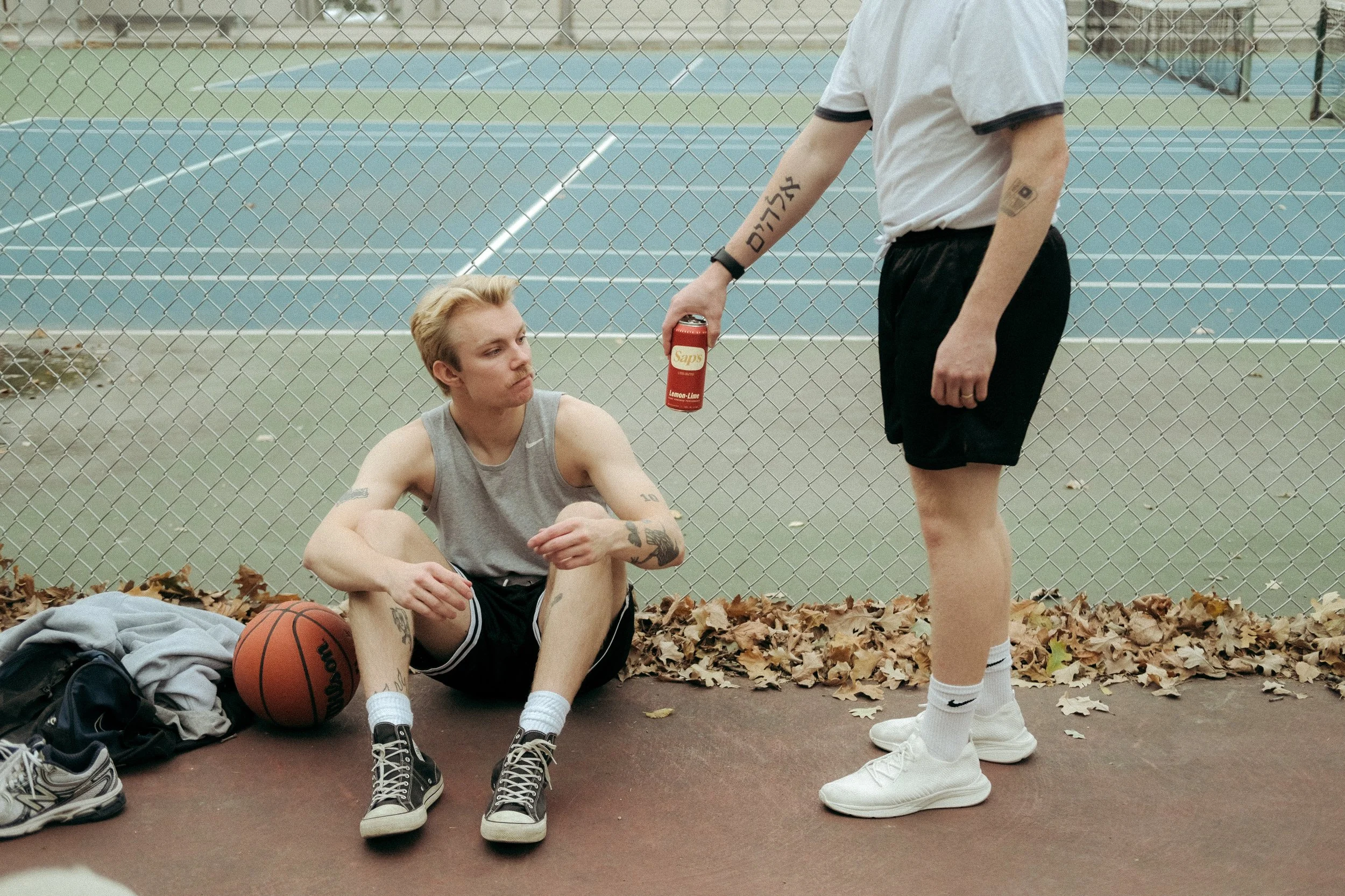 Man handing Sap's drink to friend.