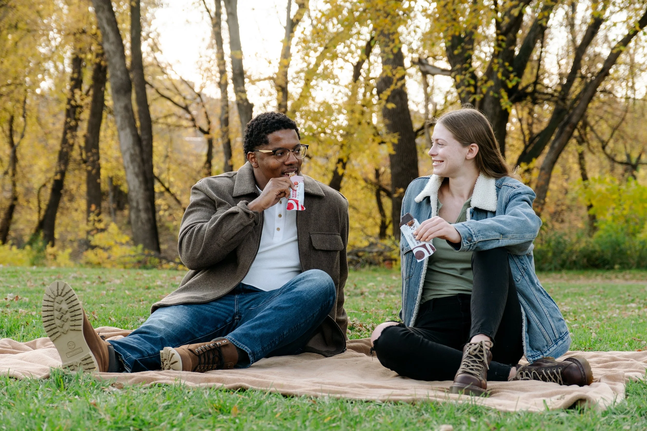 Couple eating snack in the park in the fall.