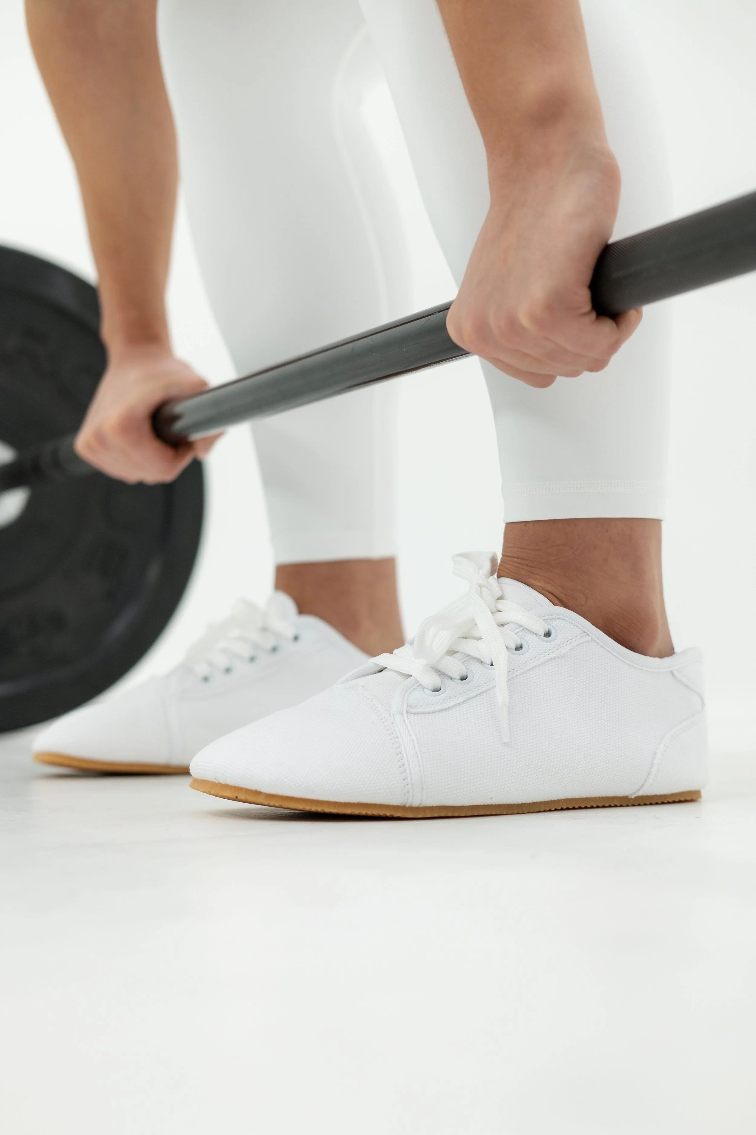 Woman deadlifting wearing Bearfoot shoes.