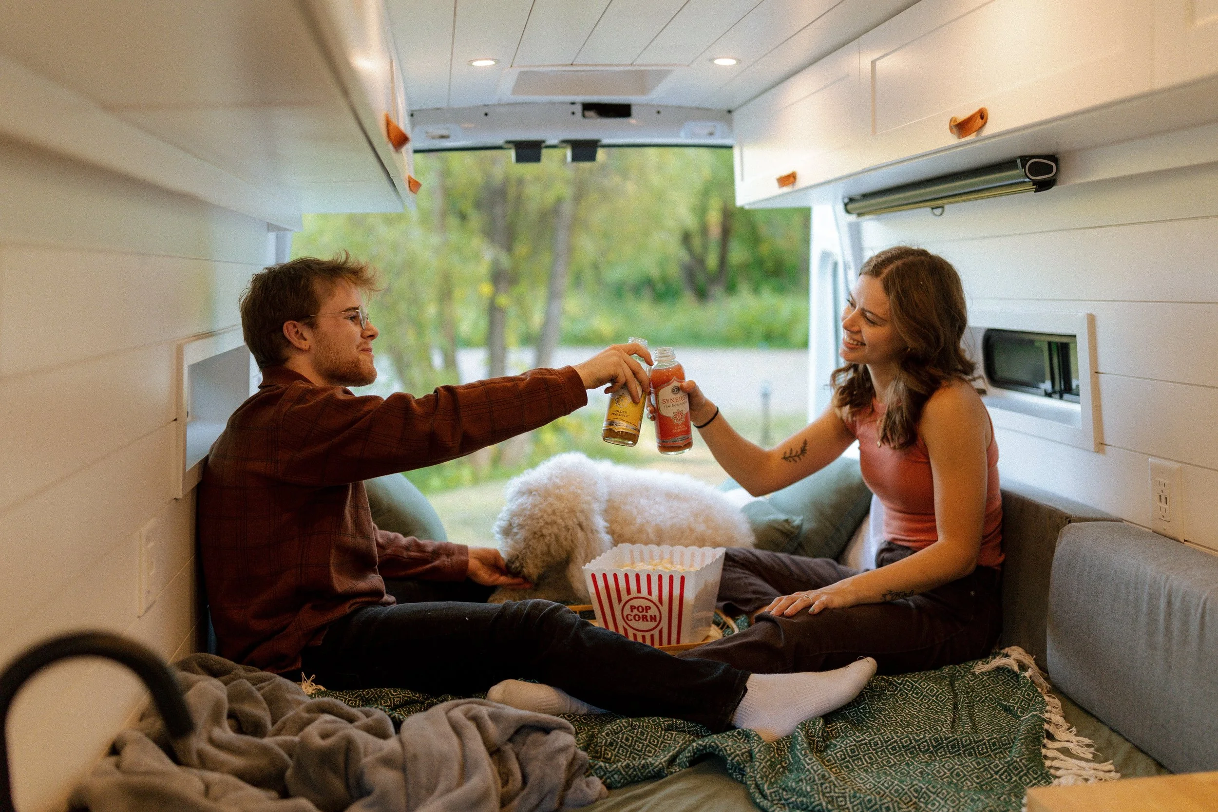 Man and woman cheersing drink in Vanna Adventure Van.