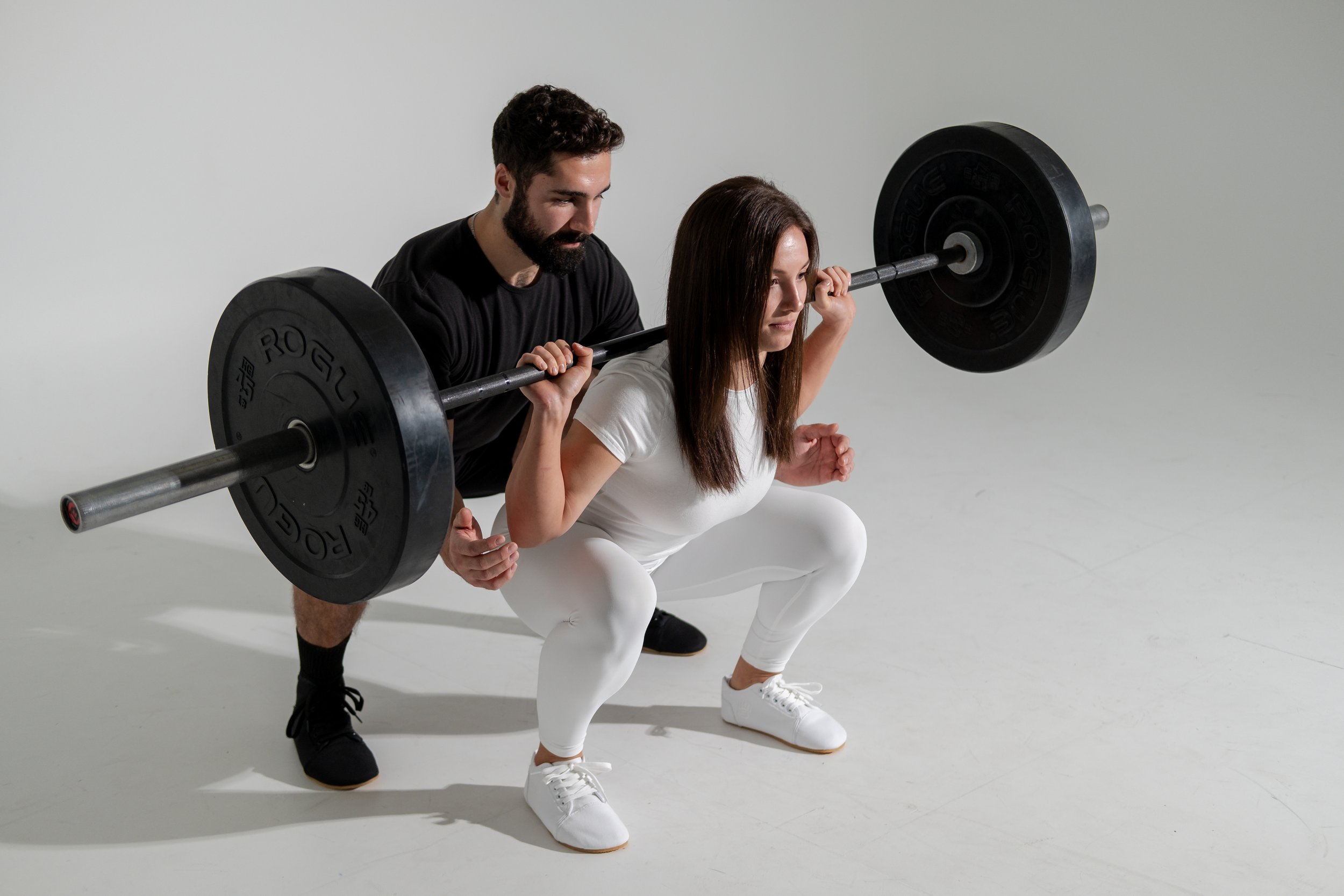 Man spotting woman squatting weights.