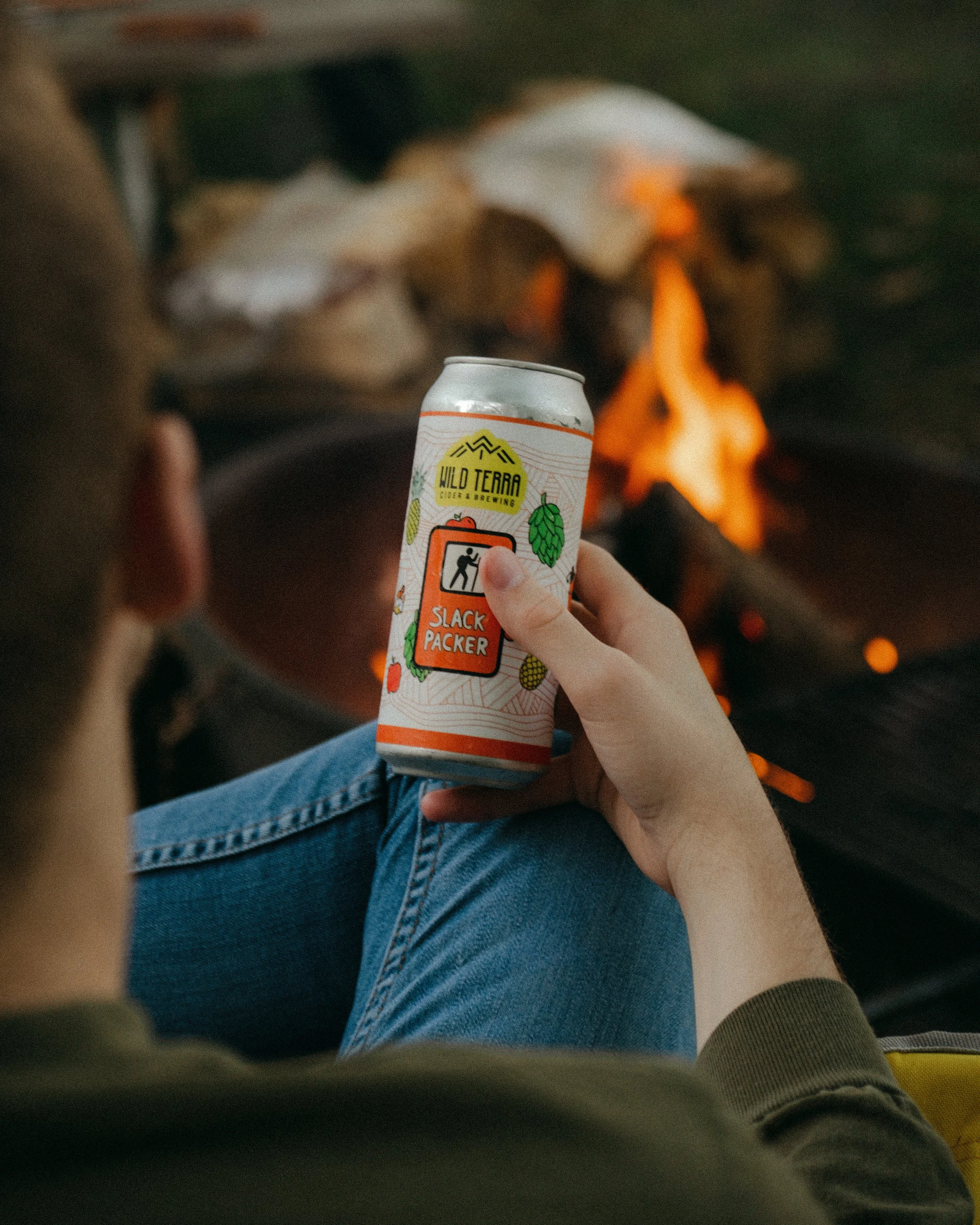 Man holding a cider by the fire.