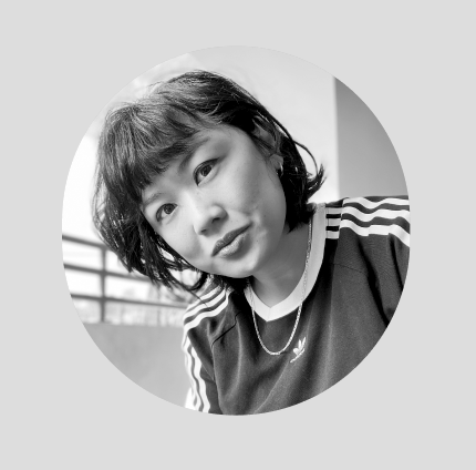 Black and white photo of a young girl with short dark hair, wearing a sports jersey, outdoors with a blurred background.