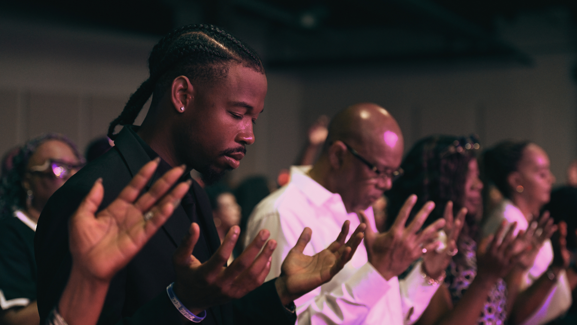 Four friends sitting on a comfortable sofa in a cozy living room, smiling at the camera while enjoying coffee mugs on a coffee table.