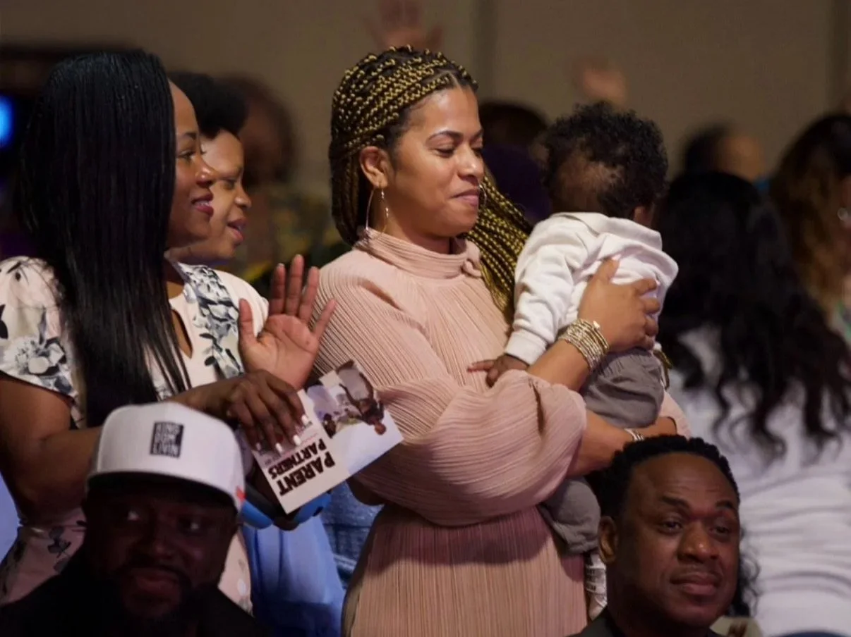 Family of four outdoors in a yard, smiling and posing for a photo.