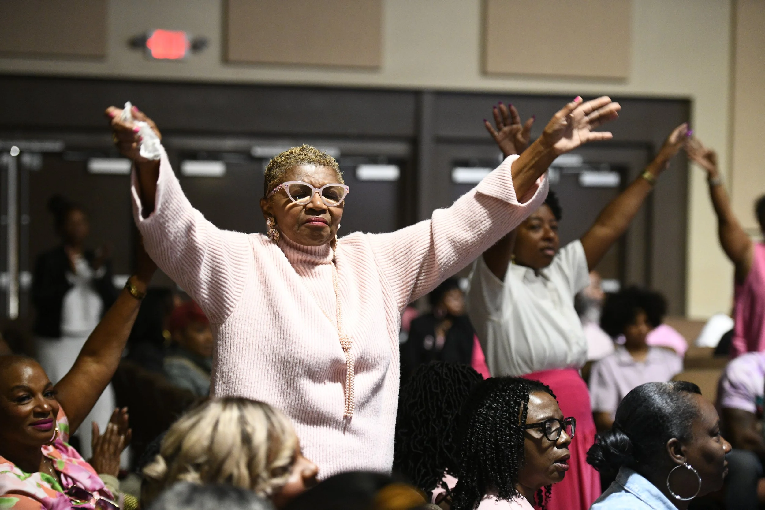 A young man and woman jogging outdoors on a sunny day, with trees and a bridge in the background.