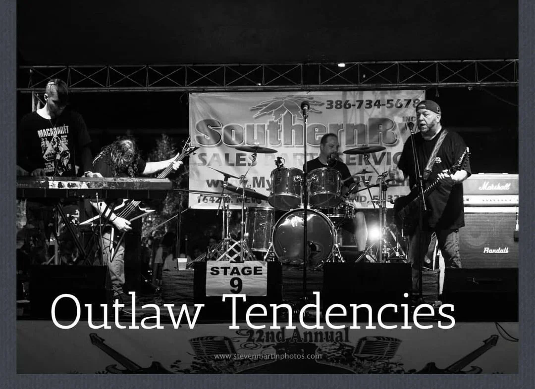 A four-member band performing on stage at an outdoor event, with drums, guitars, and keyboards, beneath a banner that reads 'Southern by Sales & Service.'