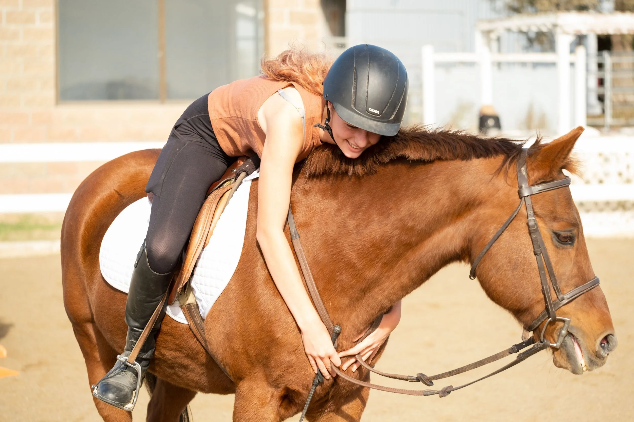 Smiling young rider hugging a chestnut horse during a lesson at Strides Riding Academy in Santa Rosa, showing connection, confidence, and horsemanship.
