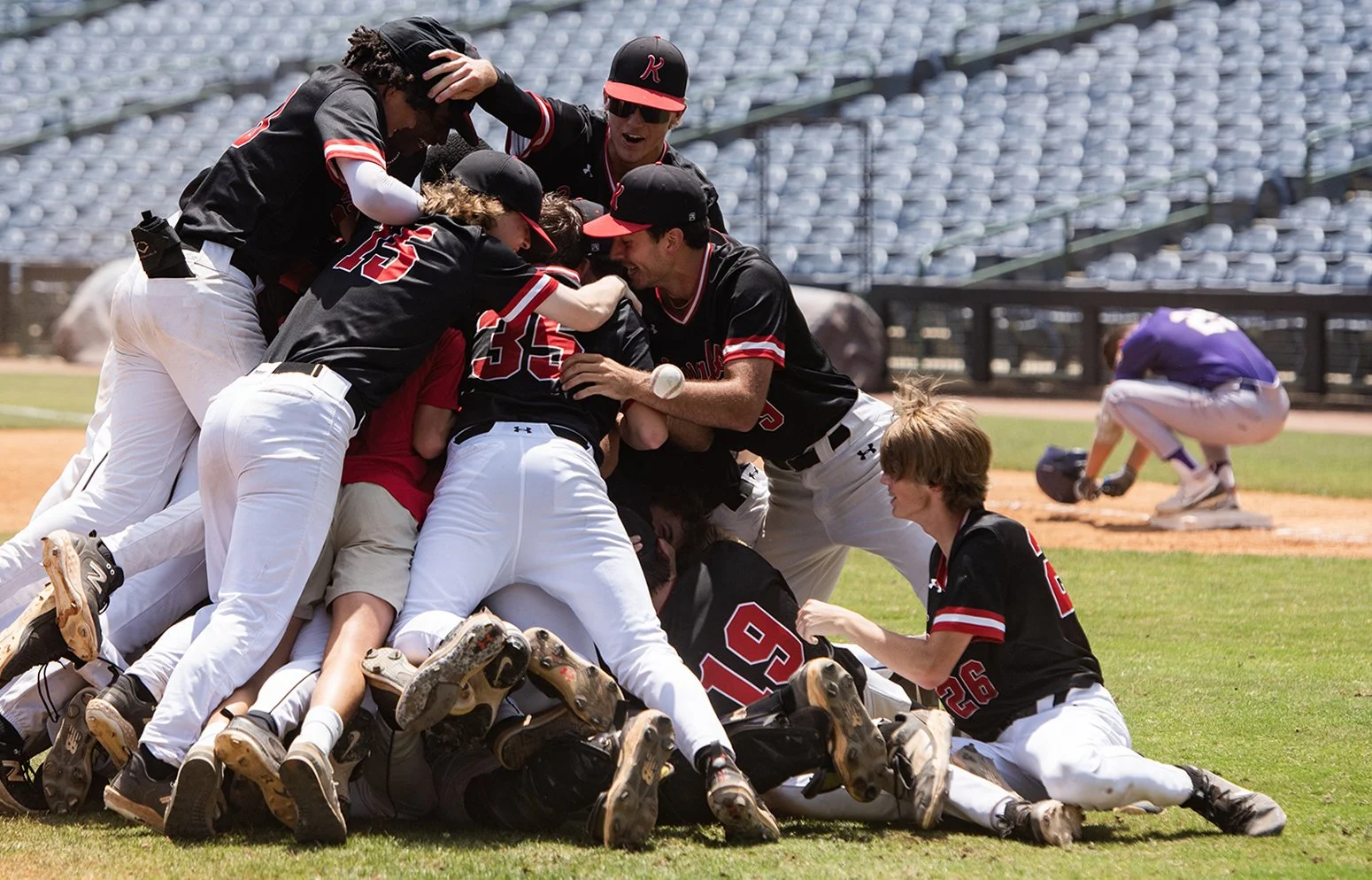  The West Lauderdale Knights celebrate while Purvis Tornadoes' Cannon Turner (25), who was the last out in the game, breaks down at first base after the Knights won the MHSAA 4A state championship game series at Trustmark Park in Pearl, Miss., on May