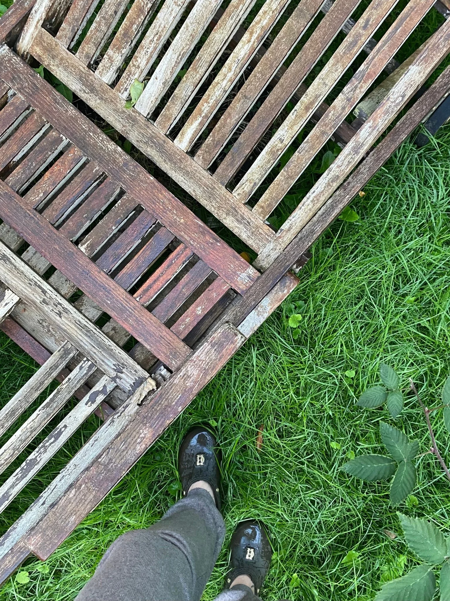 Leere Gartenliege aus altem Teakholz im Herbstgarten.