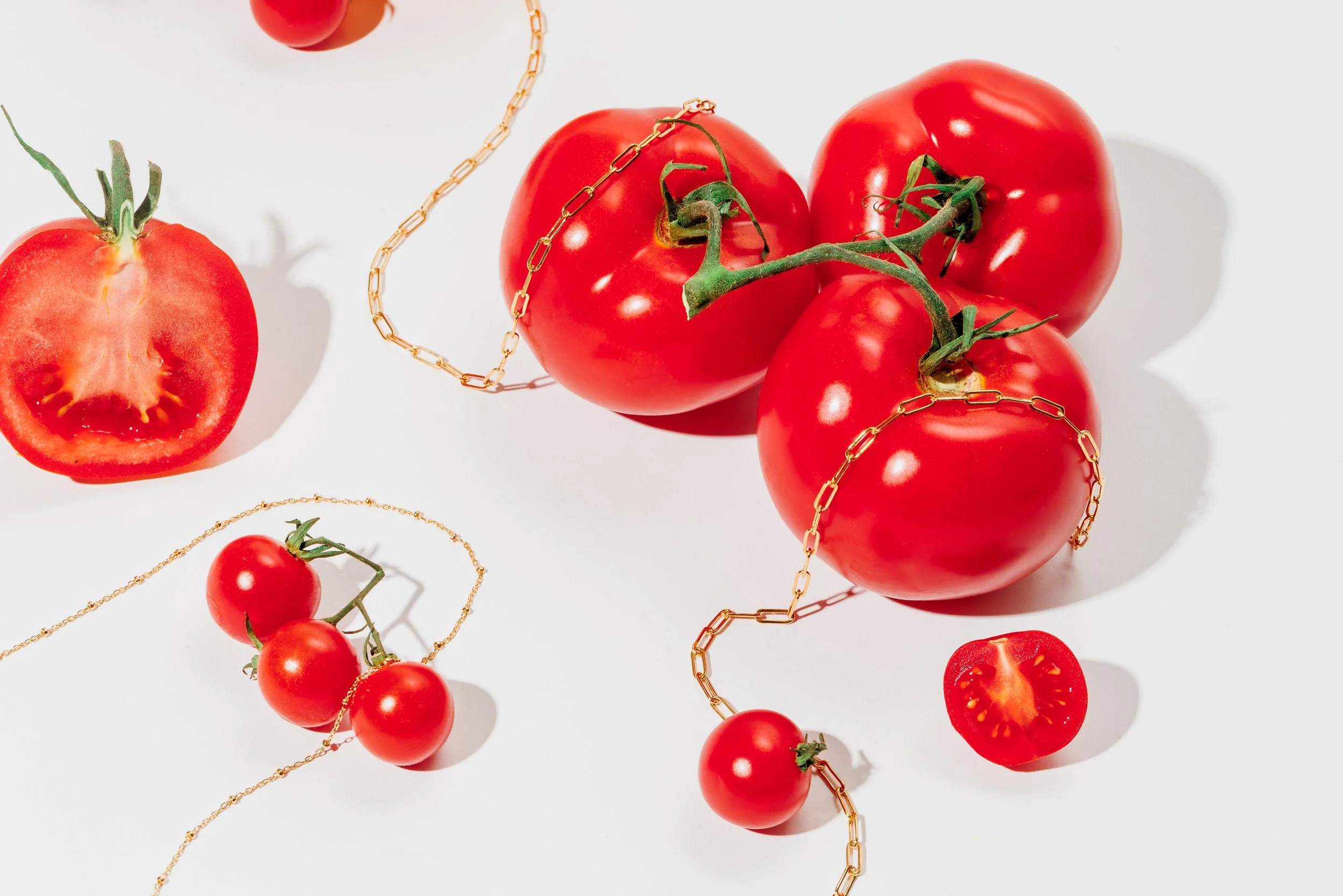 Jewelry draped over tomatoes for brand photos