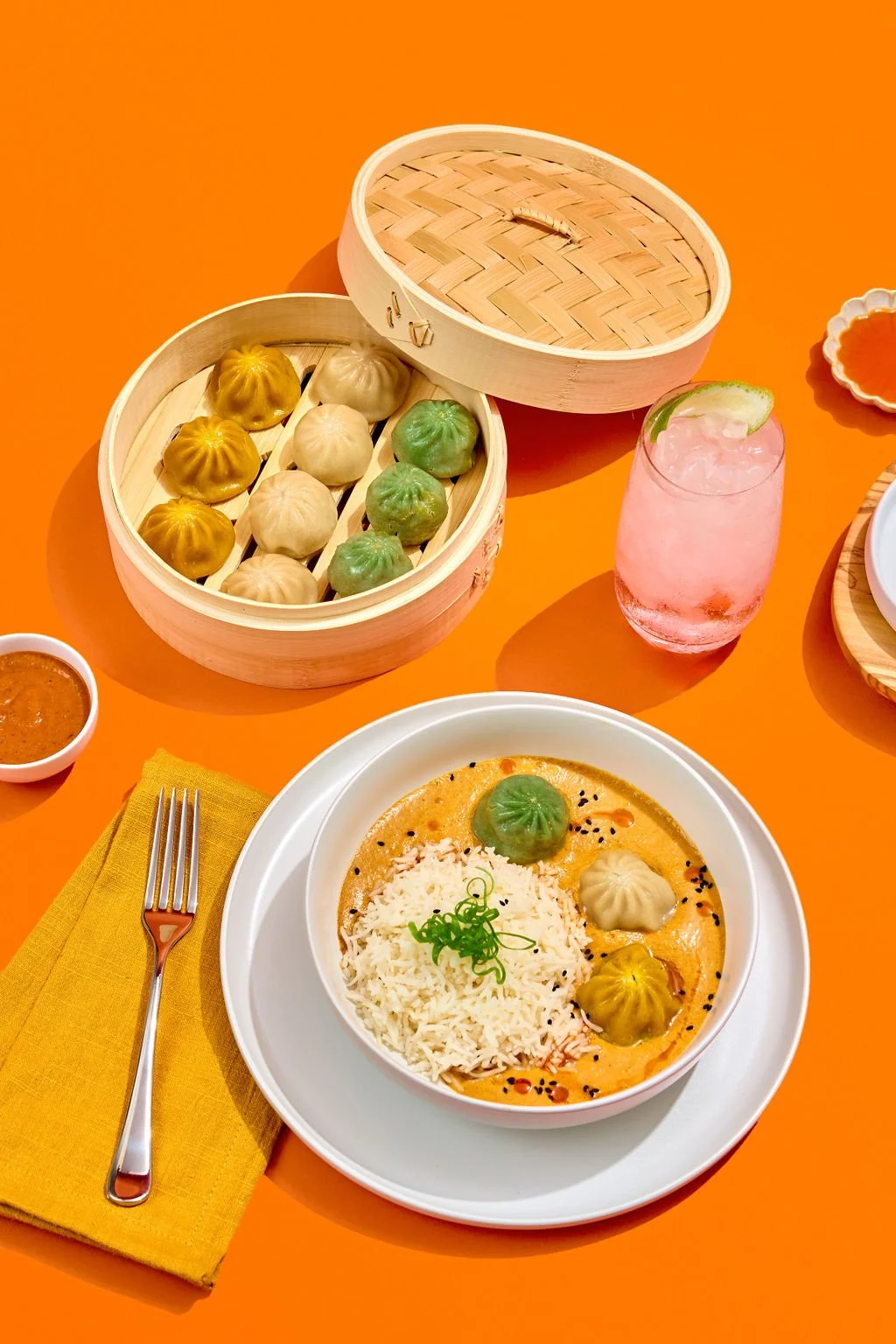 Dumplings, sauces, and drinks against an orange background