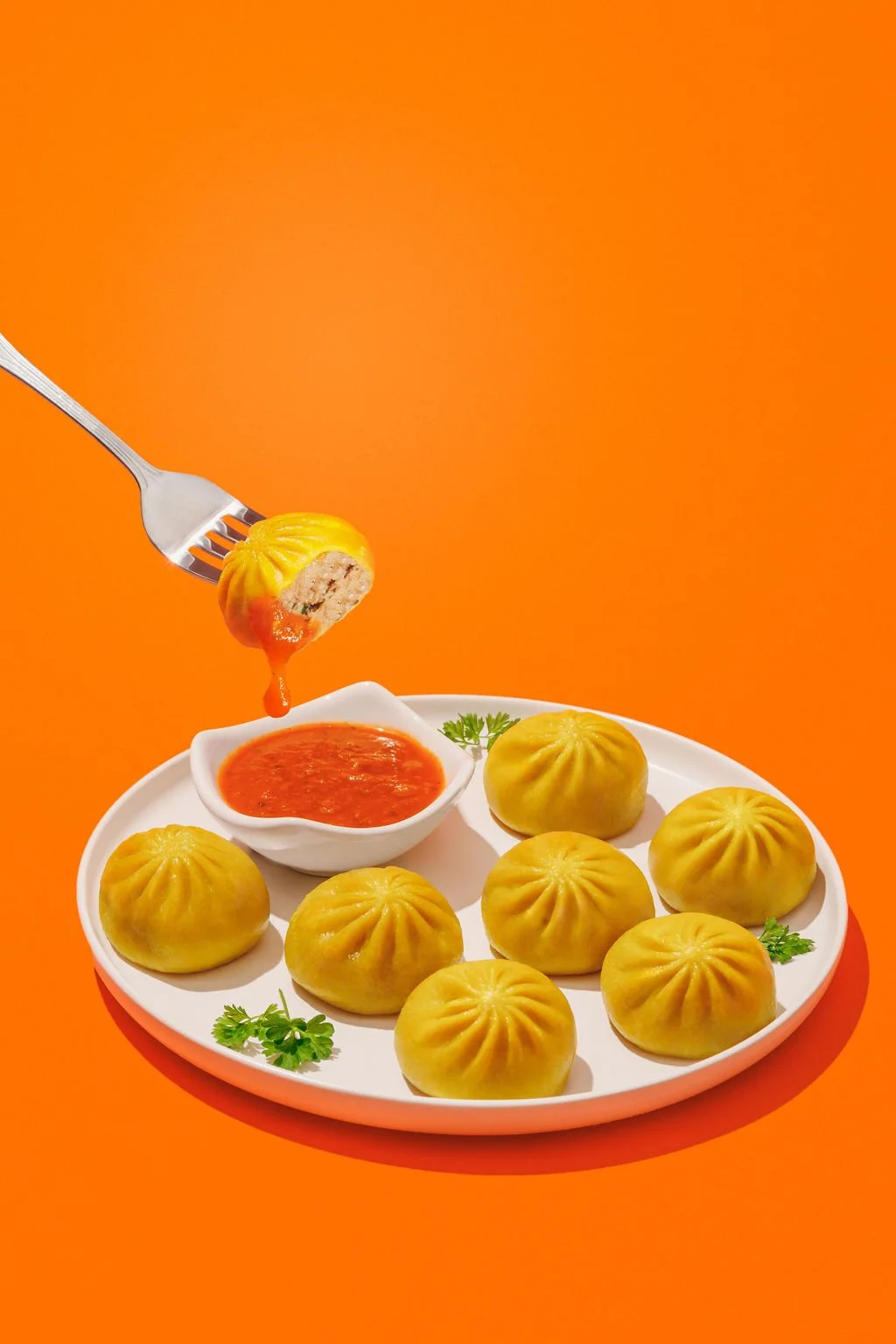 A dumpling on a fork being taken off of a plate