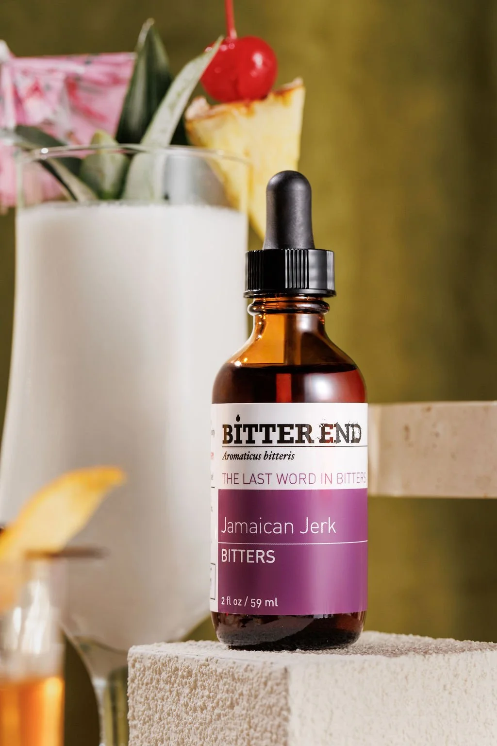 A bottle of bitters in front of a cocktail