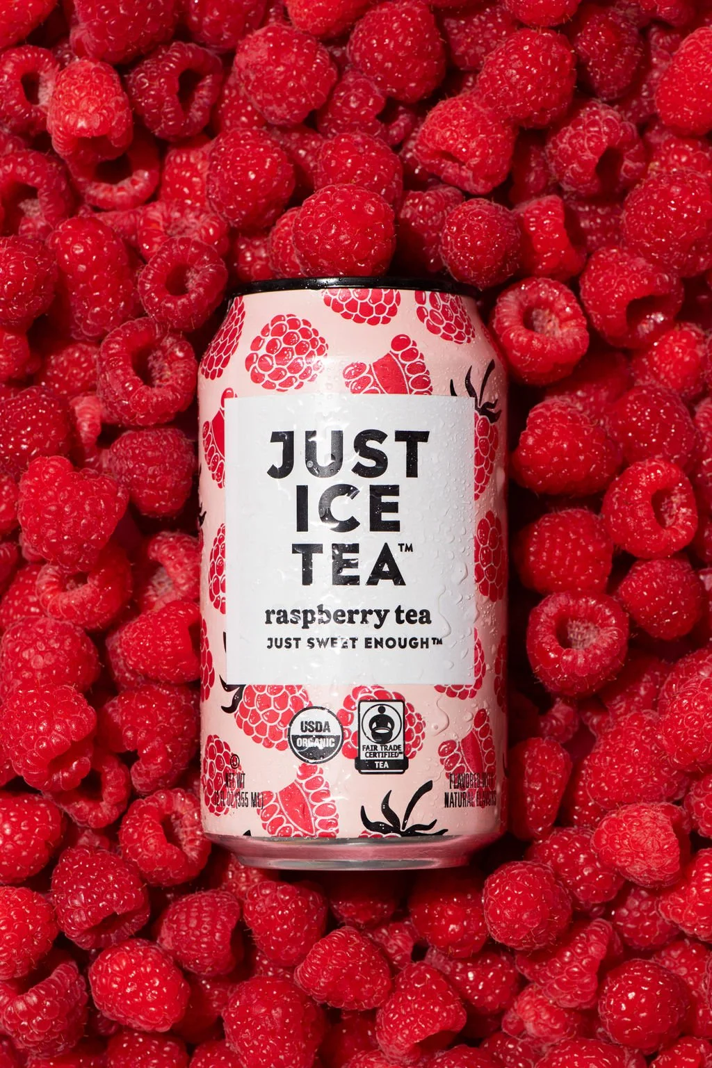 A Just Ice Tea can lying on raspberries, captured by a brand photographer