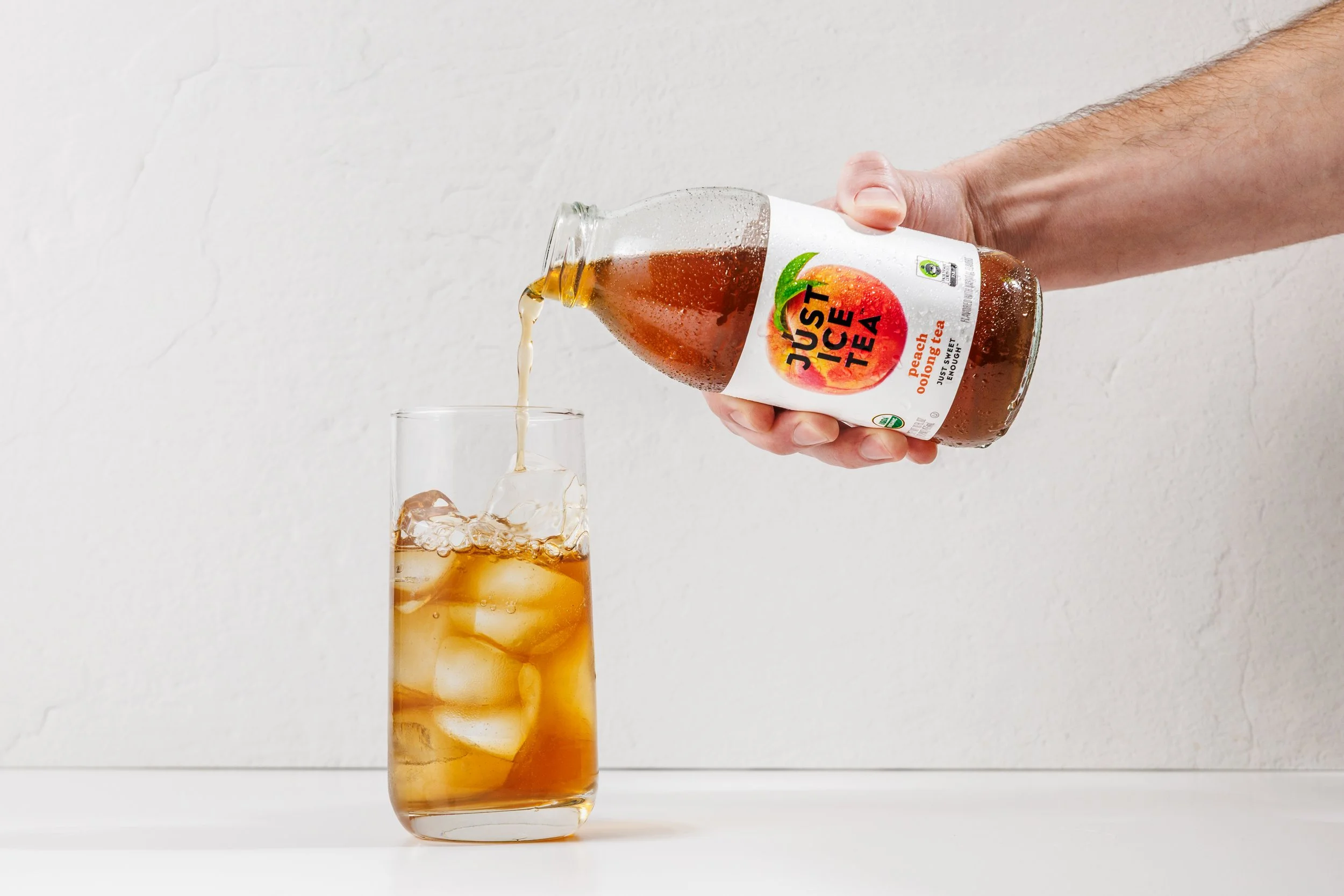 Someone pouring an iced tea into a glass of ice