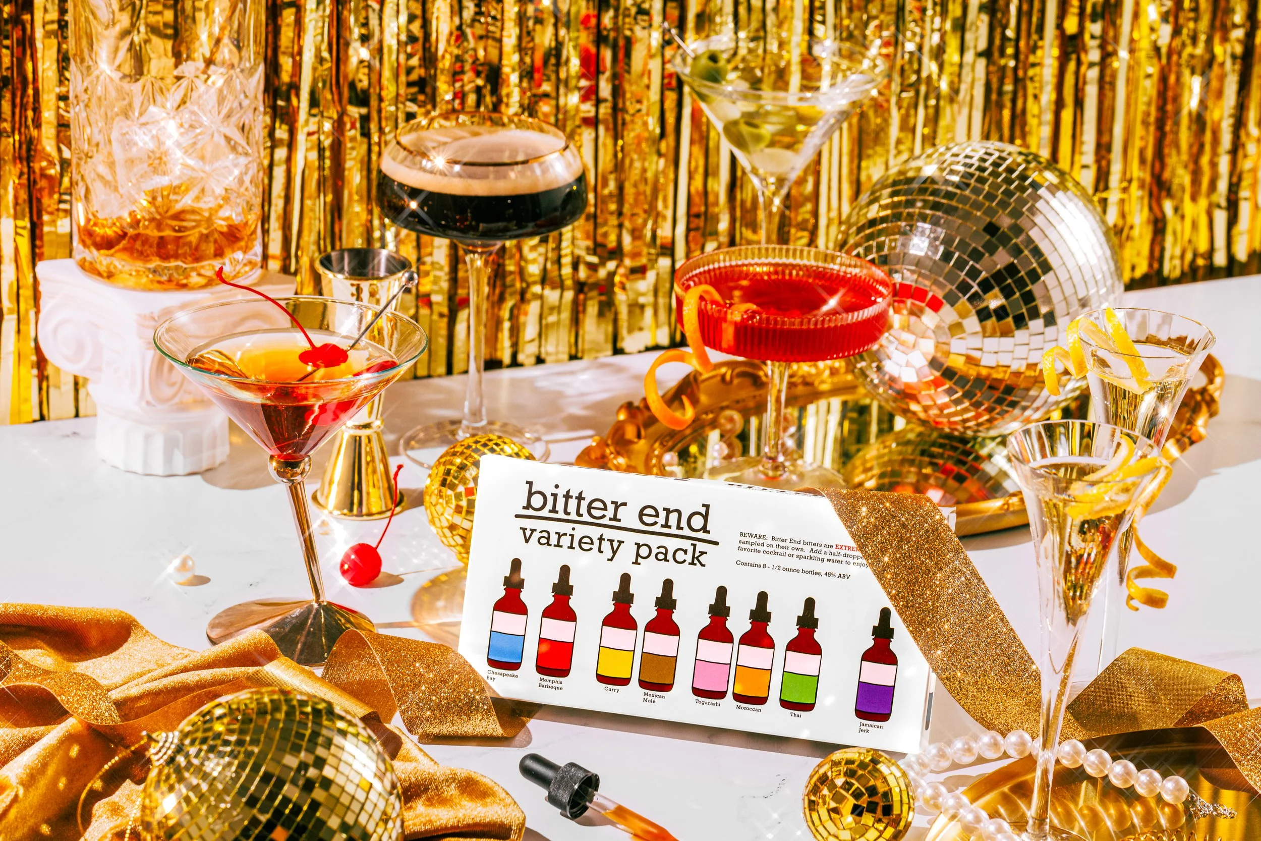 Product photos of a package of bitters surrounded by gold decor and cocktails