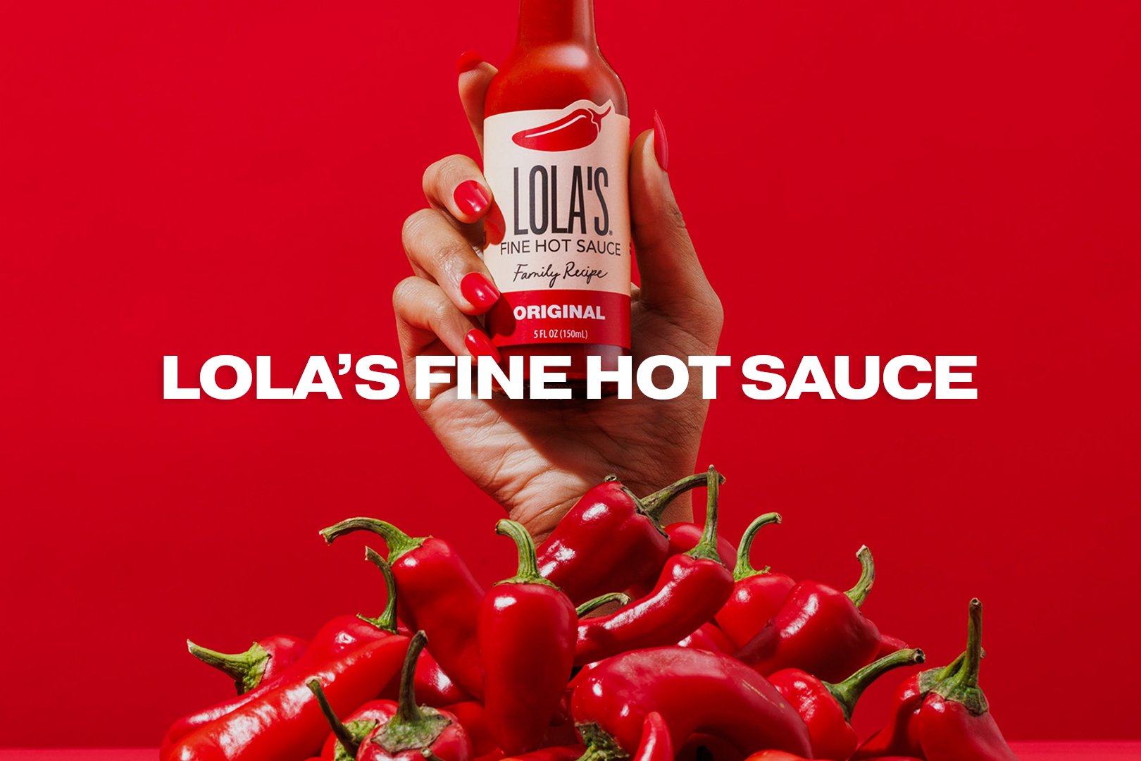 A hand with red nails holding a bottle of Lola's Fine Hot Sauce against a red background, with a pile of red chili peppers at the bottom. The text overlay says, "Lola's Fine Hot Sauce."