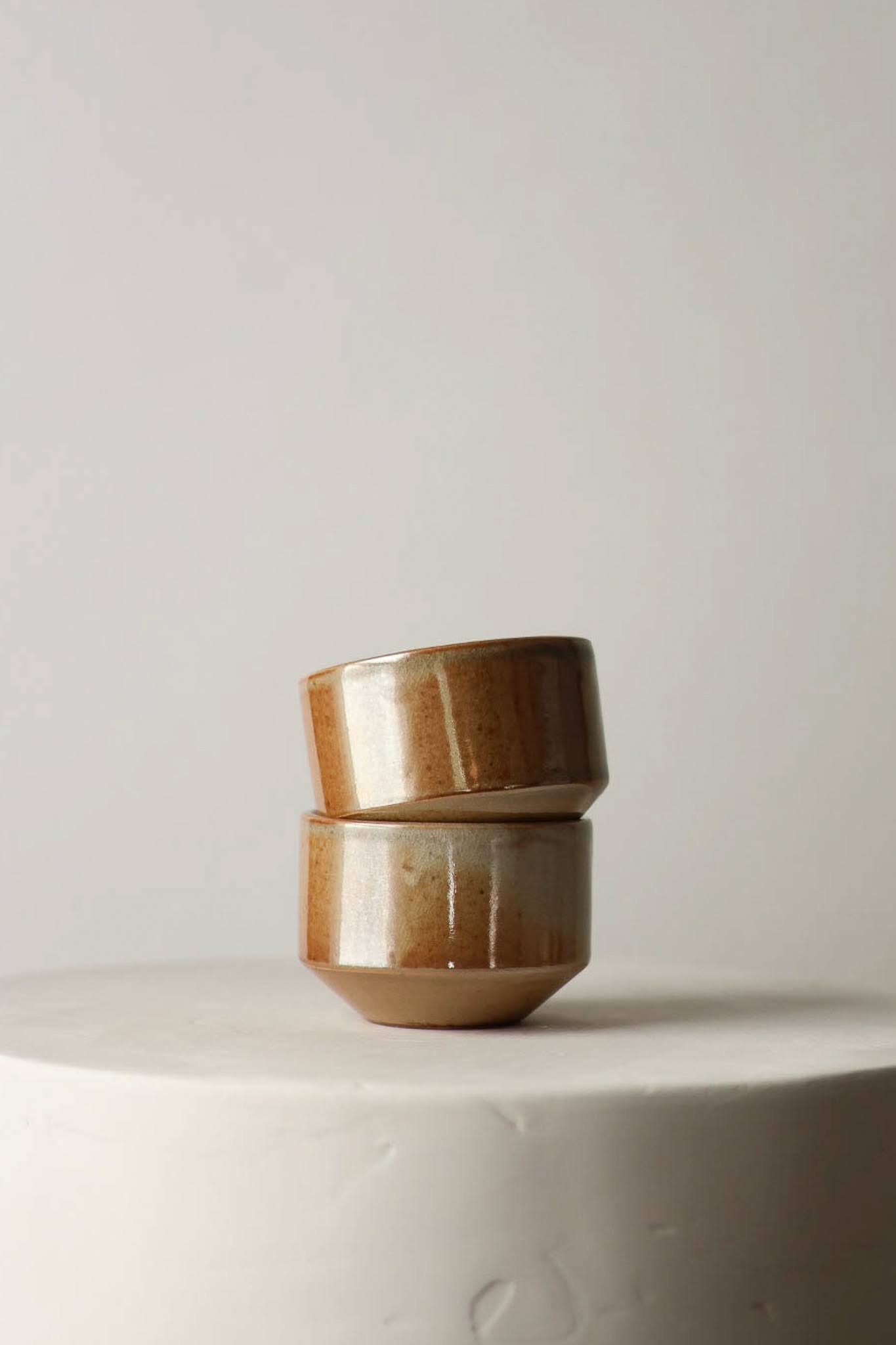 Two stacked cups in a warm tones metallic shino glaze