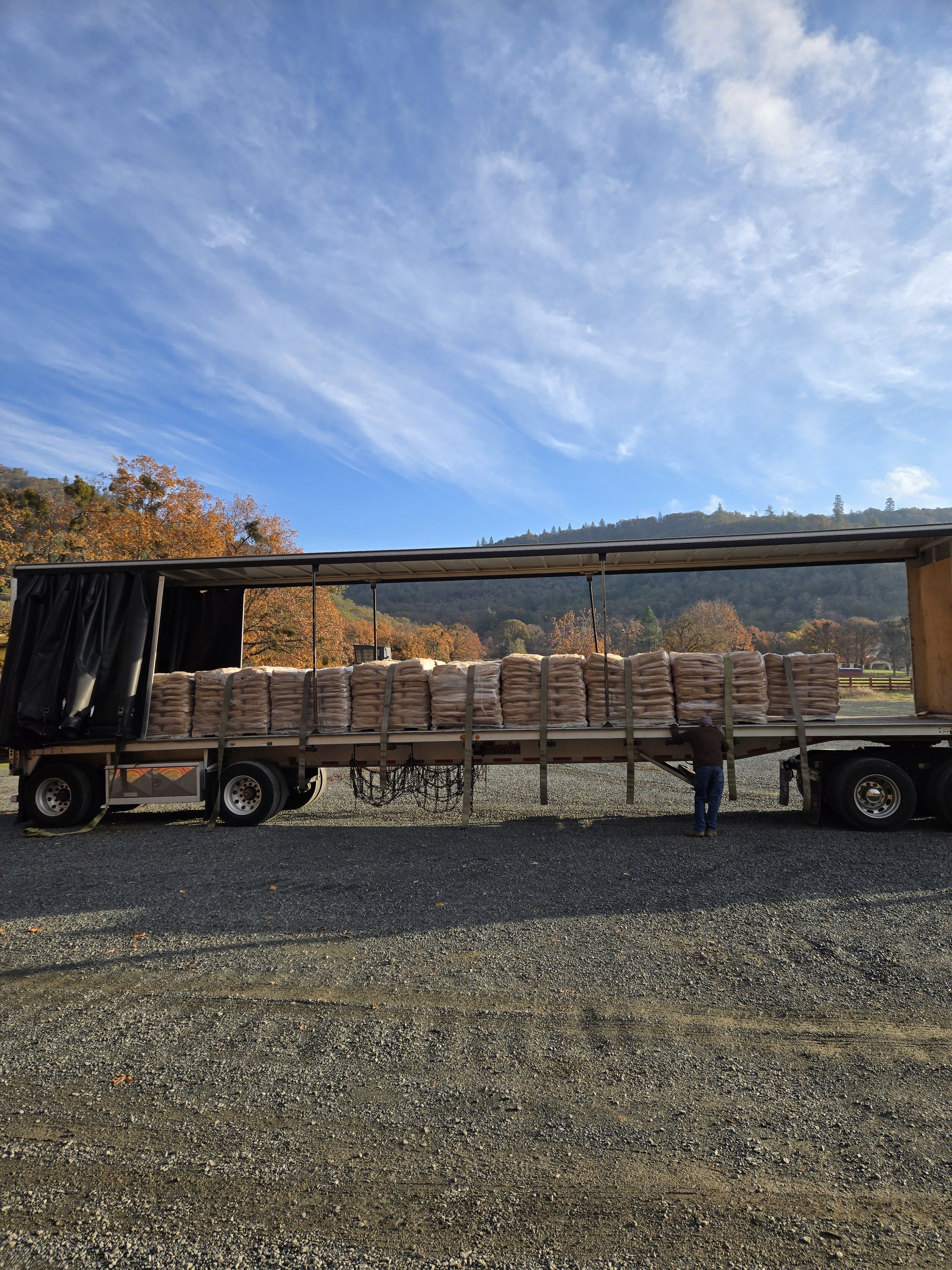 A flatbed truck carries many stacked bags full of gold hill clay plaster products