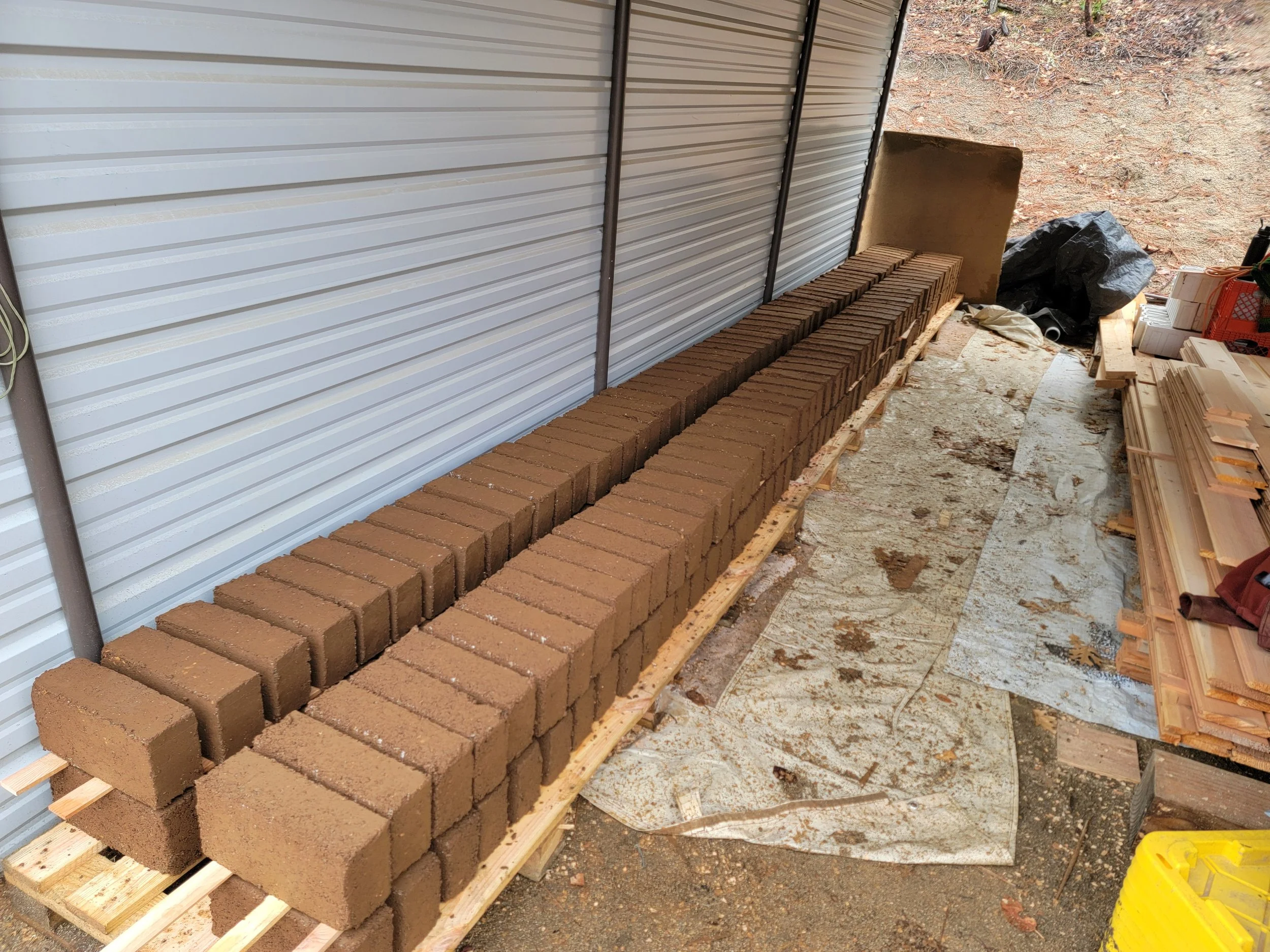 Row of freshly made bricks stacked on a wooden pallet at a construction site outdoors.