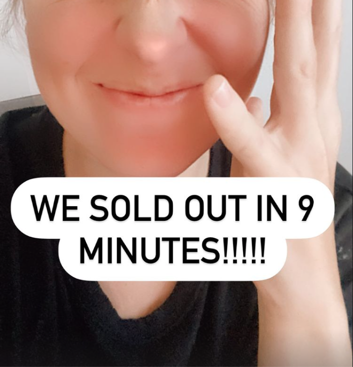 Close-up of a smiling woman with short hair making a peace sign with her fingers. Text overlay says, "WE SOLD OUT IN 9 MINUTES!!!!!"