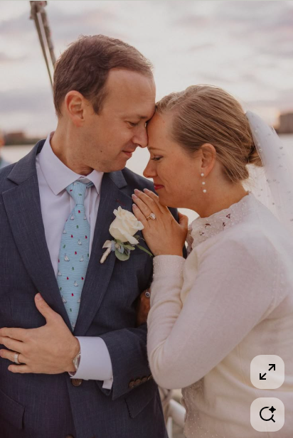 A bride and groom standing close together with foreheads touching, eyes closed, during their wedding ceremony outdoors.
