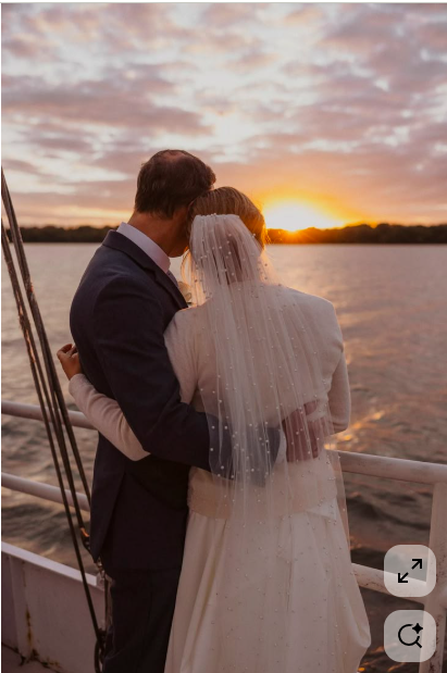 Bride and groom hugging on a boat during sunset.